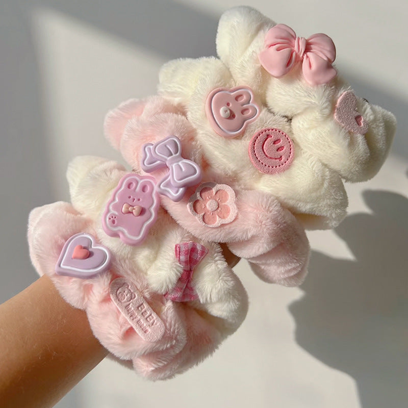 A pink and white plush hair tie featuring a cute animal design, perfect for adding a playful touch to hairstyles.