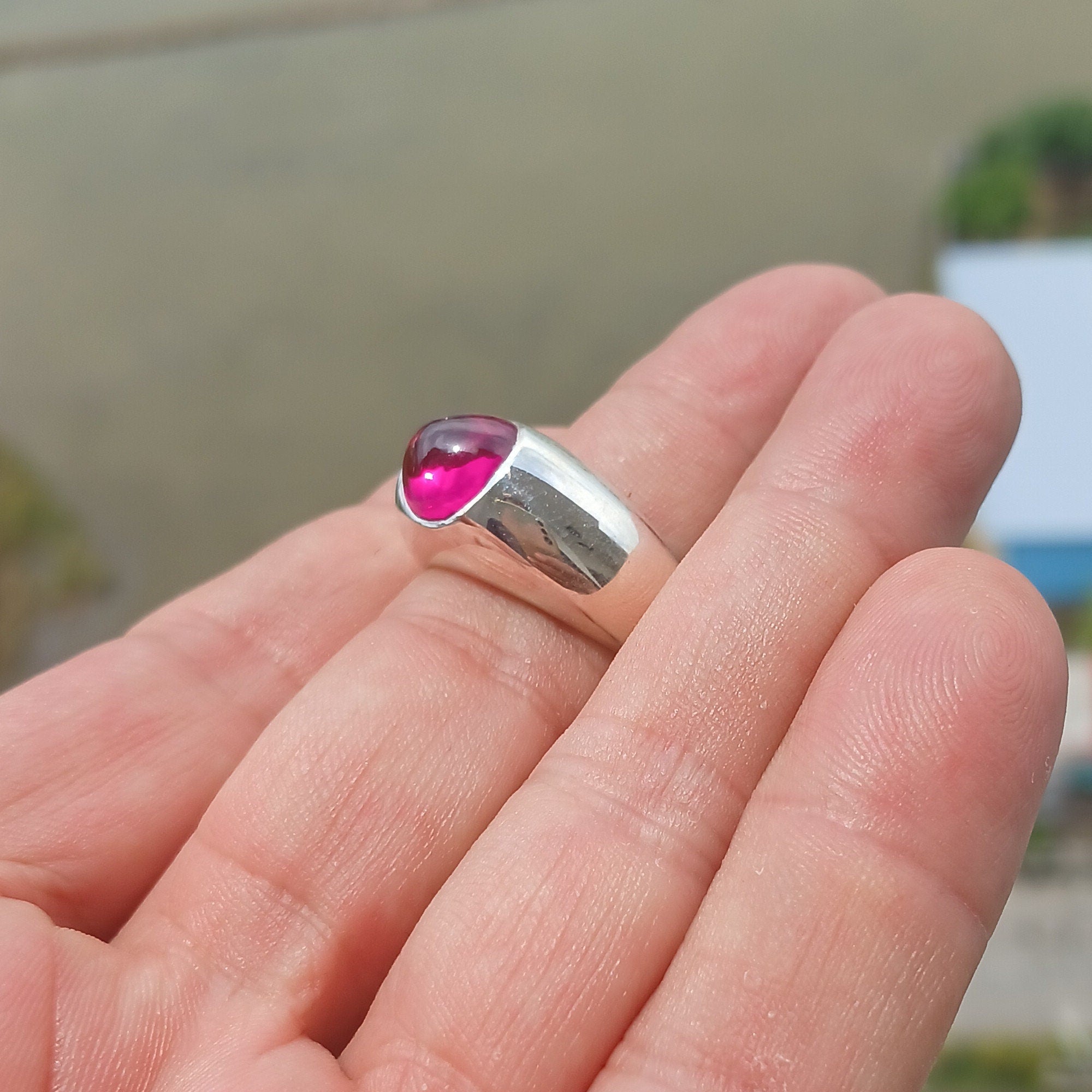 A beautiful Pink CZ Cabochon Ring made of sterling silver, featuring an oval-shaped pink gemstone in a minimalist solitaire design.