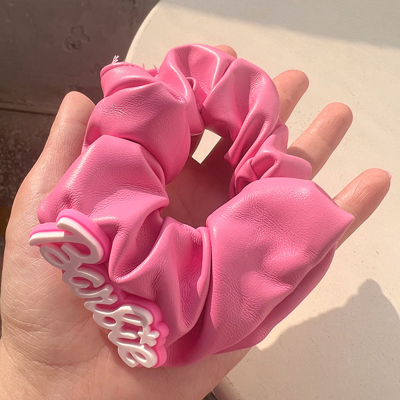 A stylish pink hair tie with a unique textured design, perfect for securing hair in place while adding a fashionable touch.