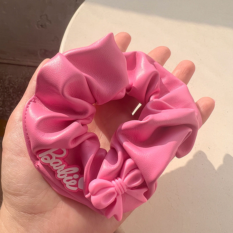 A stylish pink hair tie with a unique textured design, perfect for securing hair in place while adding a fashionable touch.