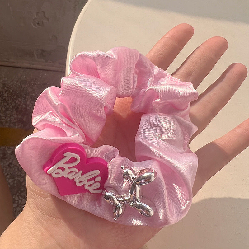 A stylish pink hair tie with a unique textured design, perfect for securing hair in place while adding a fashionable touch.