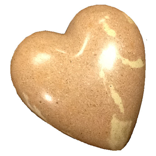 A beautifully crafted pink soapstone heart, handmade by Haitian artisans, showcasing smooth curves and a vibrant color.