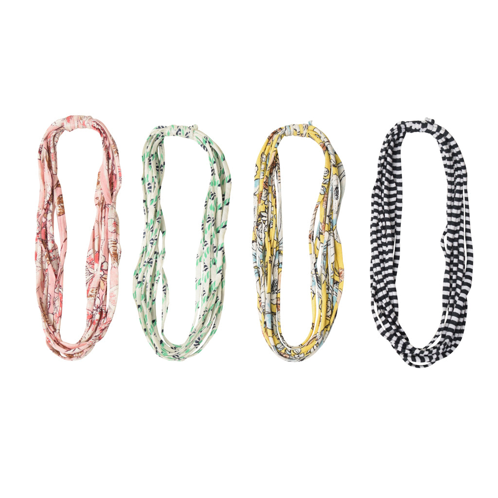 A colorful assortment of Prints + Patterns Bela Bands, showcasing their versatility as headbands and bracelets.