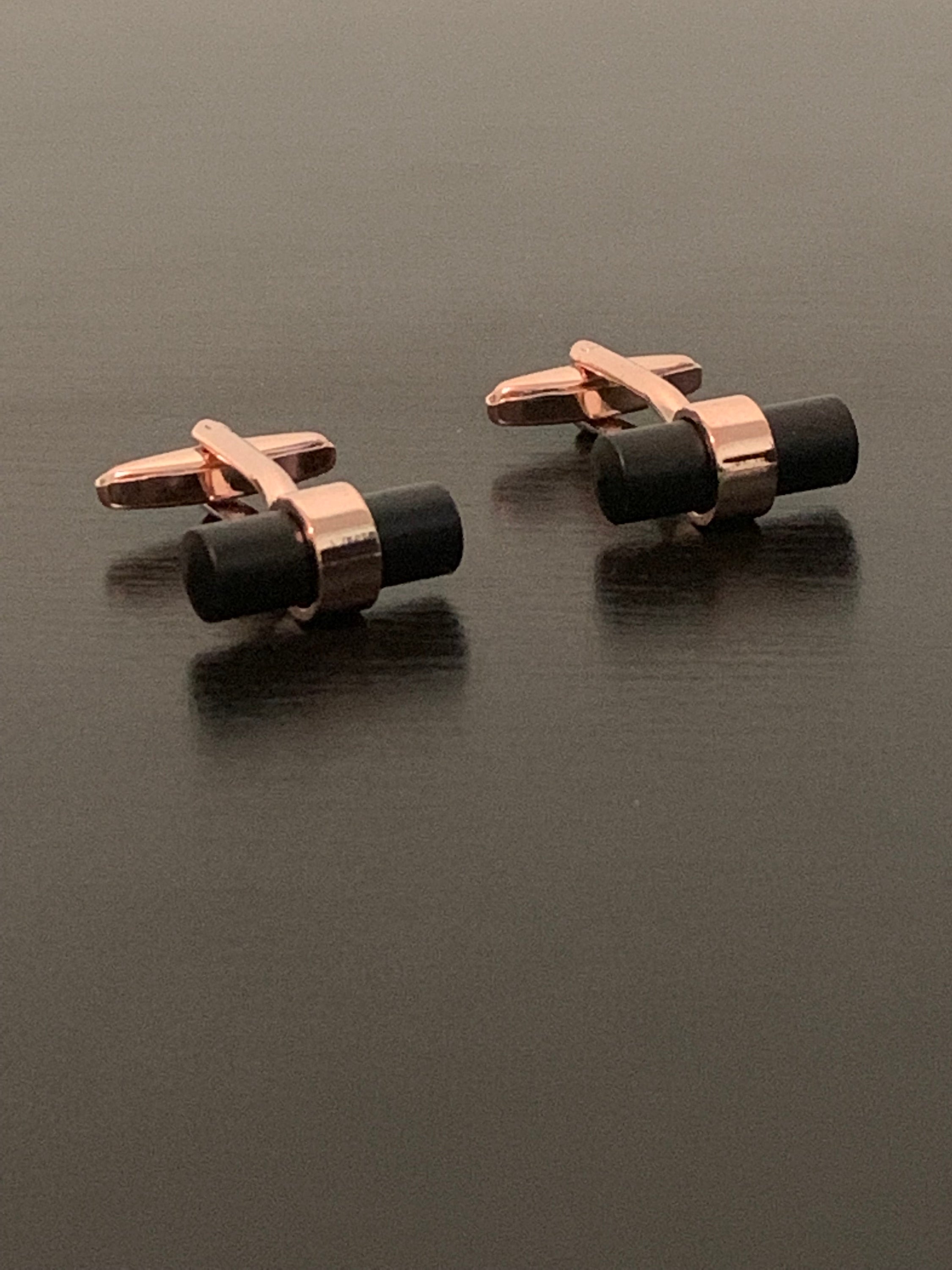 Elegant rose-gold cufflinks with a distinctive black bar design, symbolizing personal growth and sophistication.