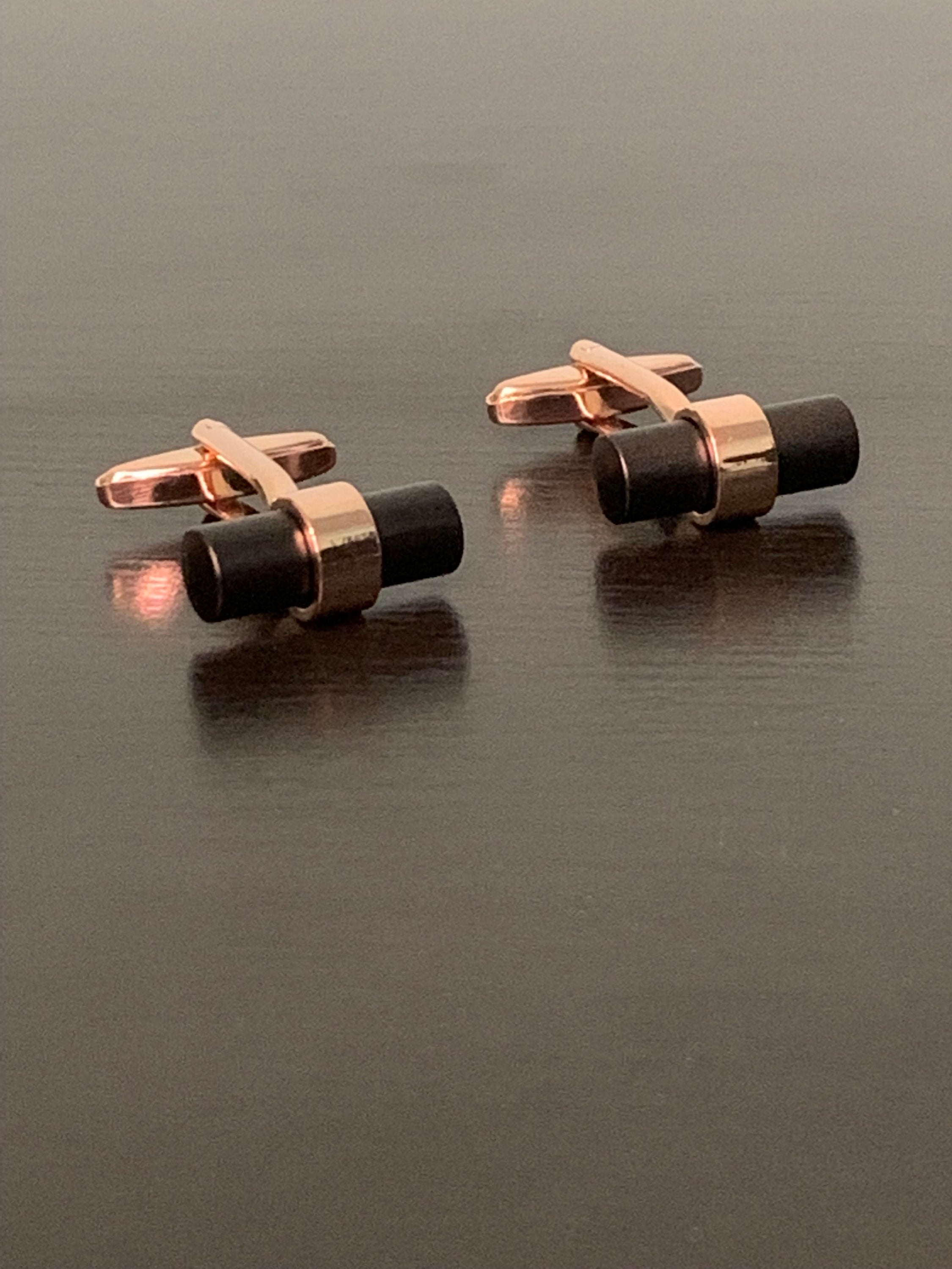 Elegant rose-gold cufflinks with a distinctive black bar design, symbolizing personal growth and sophistication.