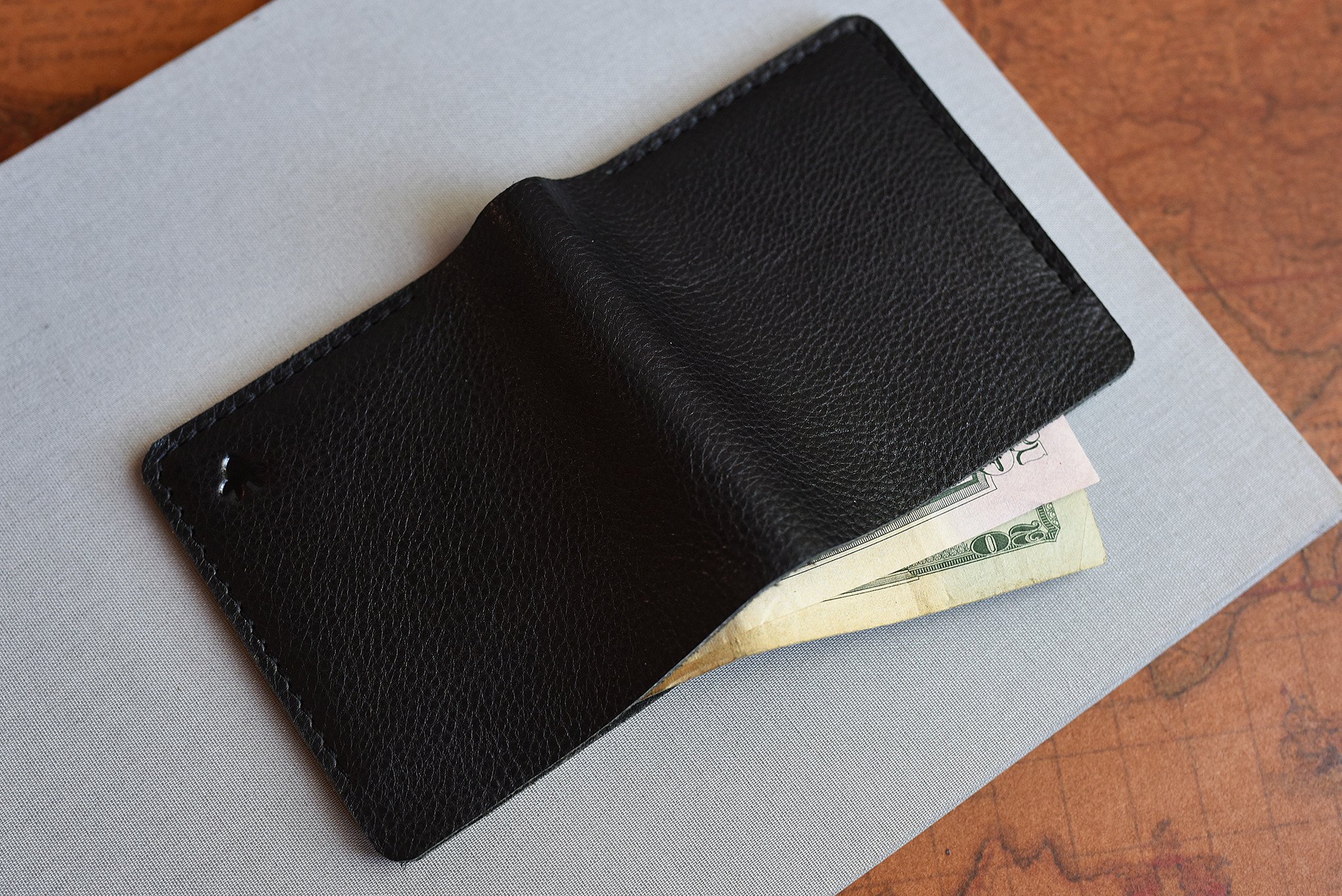 A sleek black leather Ram Wallet with two card slots and a bill compartment, showcasing its minimalistic design.