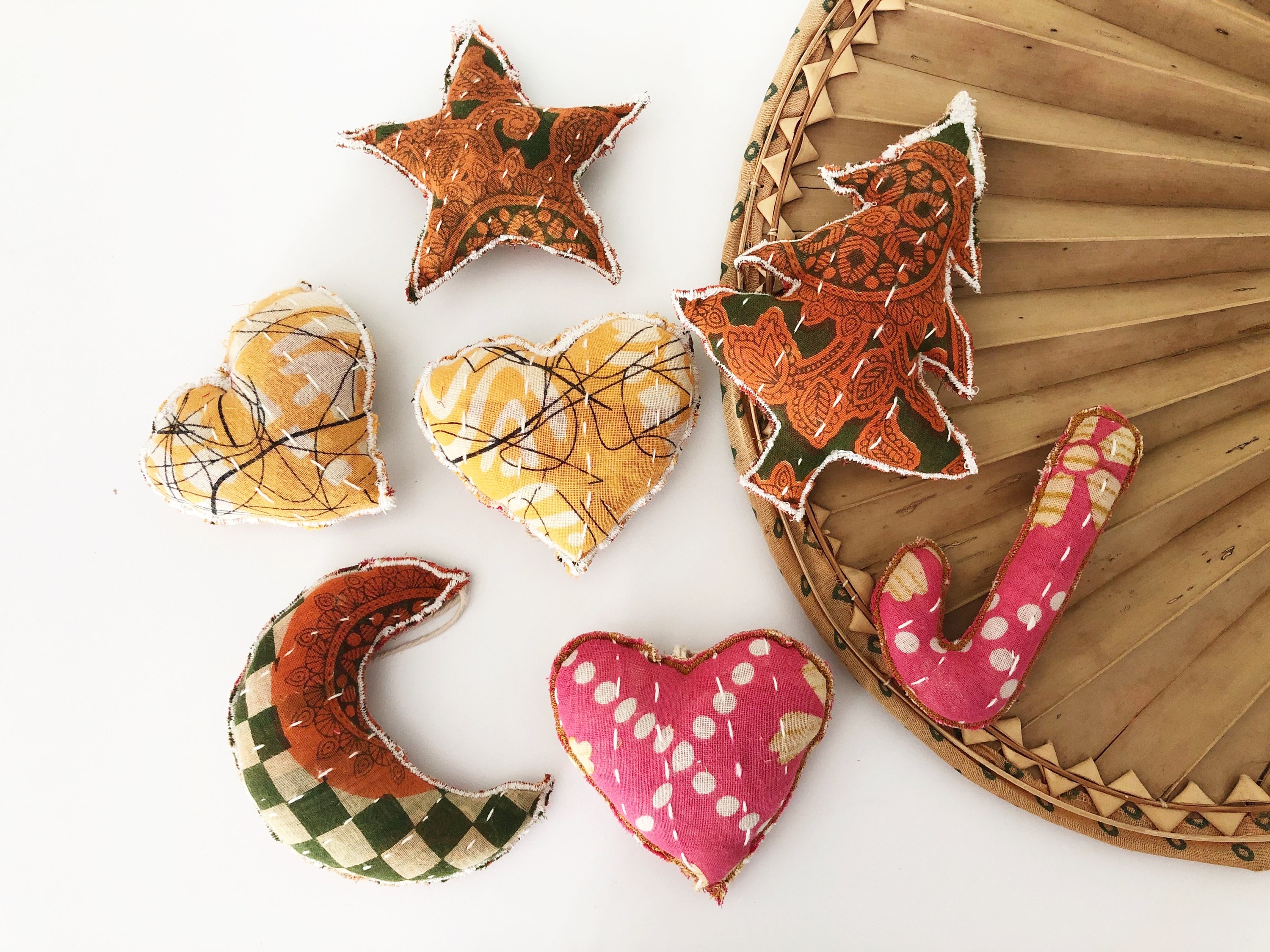 A collection of unique Recycled Fabric Ornaments made from colorful Kantha fabric scraps, featuring various shapes like stars, hearts, and trees.