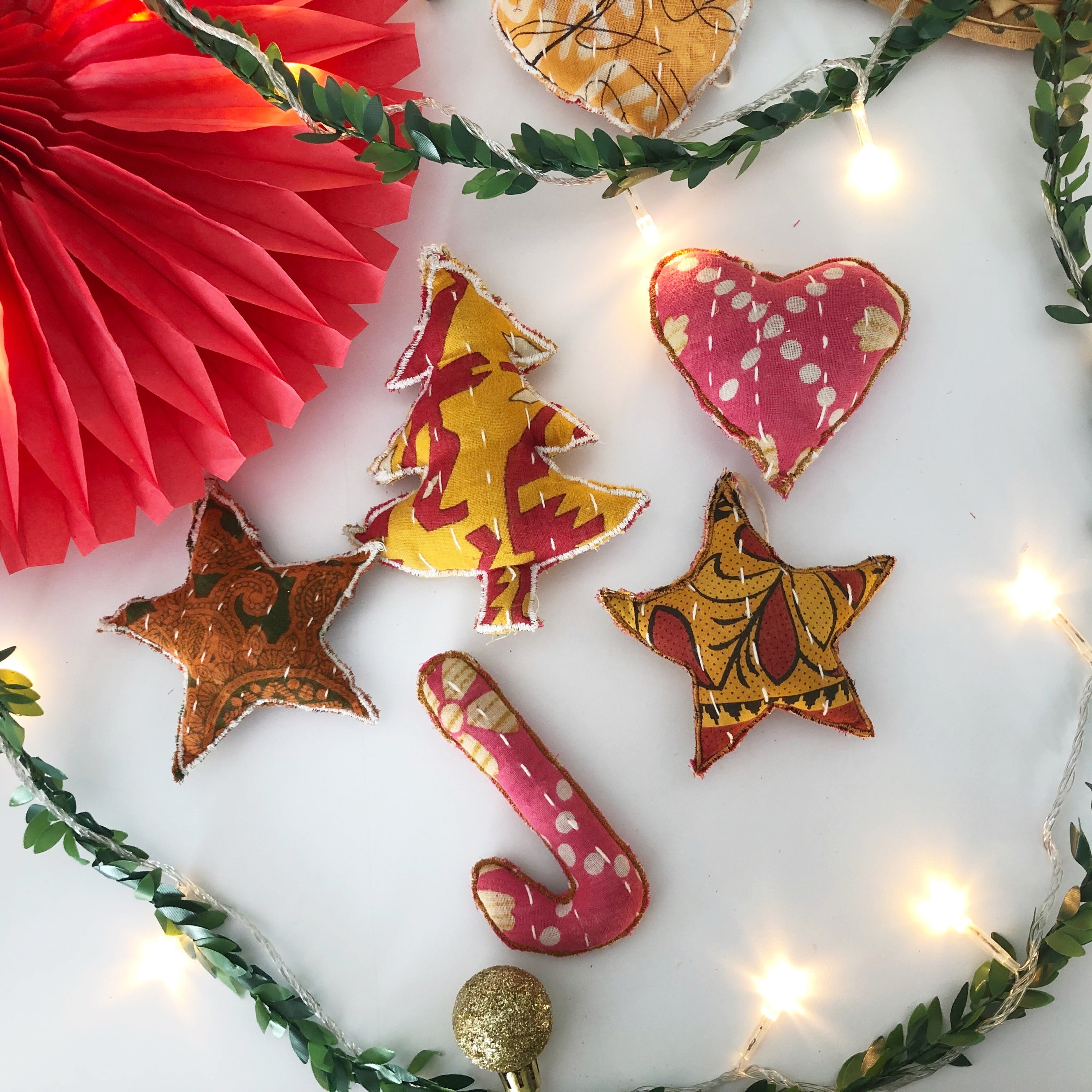 A collection of unique Recycled Fabric Ornaments made from colorful Kantha fabric scraps, featuring various shapes like stars, hearts, and trees.