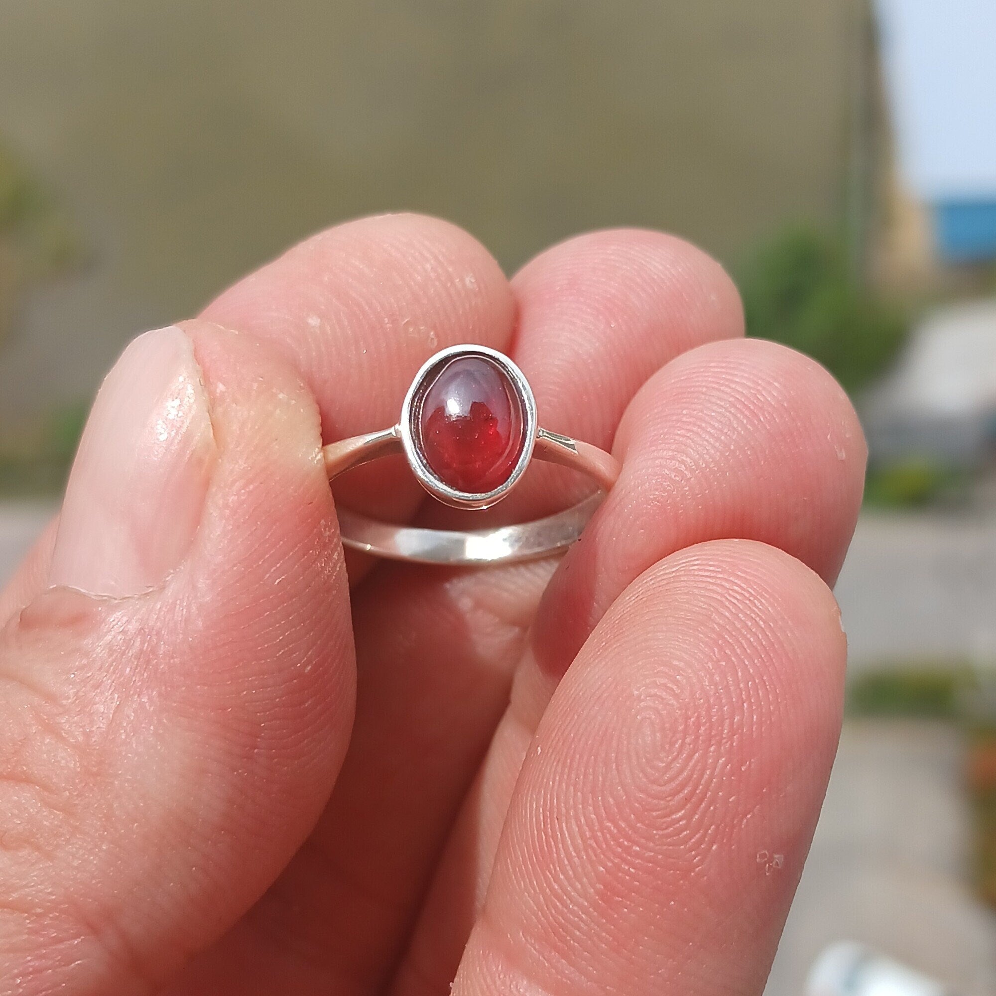 A stunning red Garnet ring set in polished sterling silver, featuring an oval-shaped Garnet cabochon and a sleek band design.