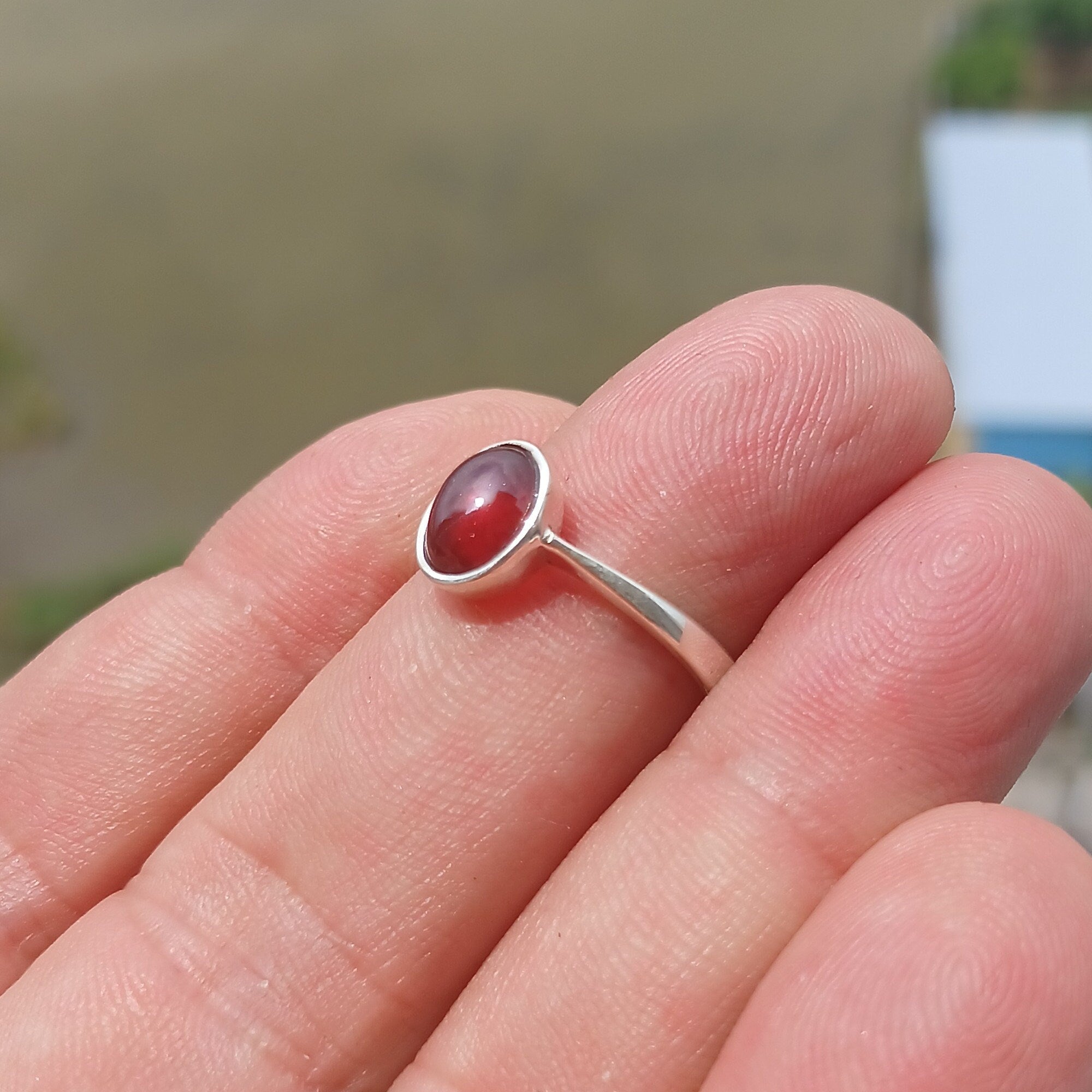 A stunning red Garnet ring set in polished sterling silver, featuring an oval-shaped Garnet cabochon and a sleek band design.