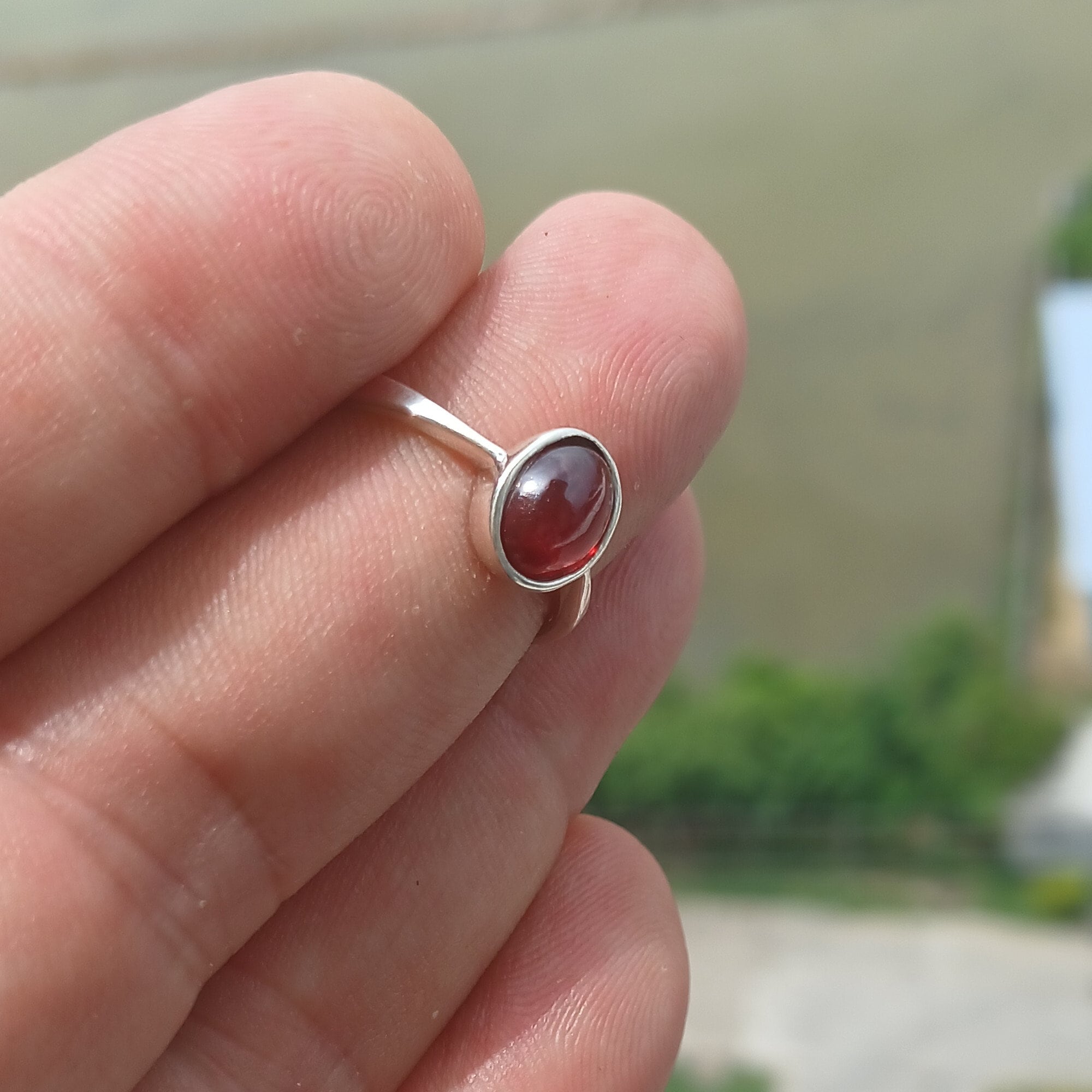 A stunning red Garnet ring set in polished sterling silver, featuring an oval-shaped Garnet cabochon and a sleek band design.