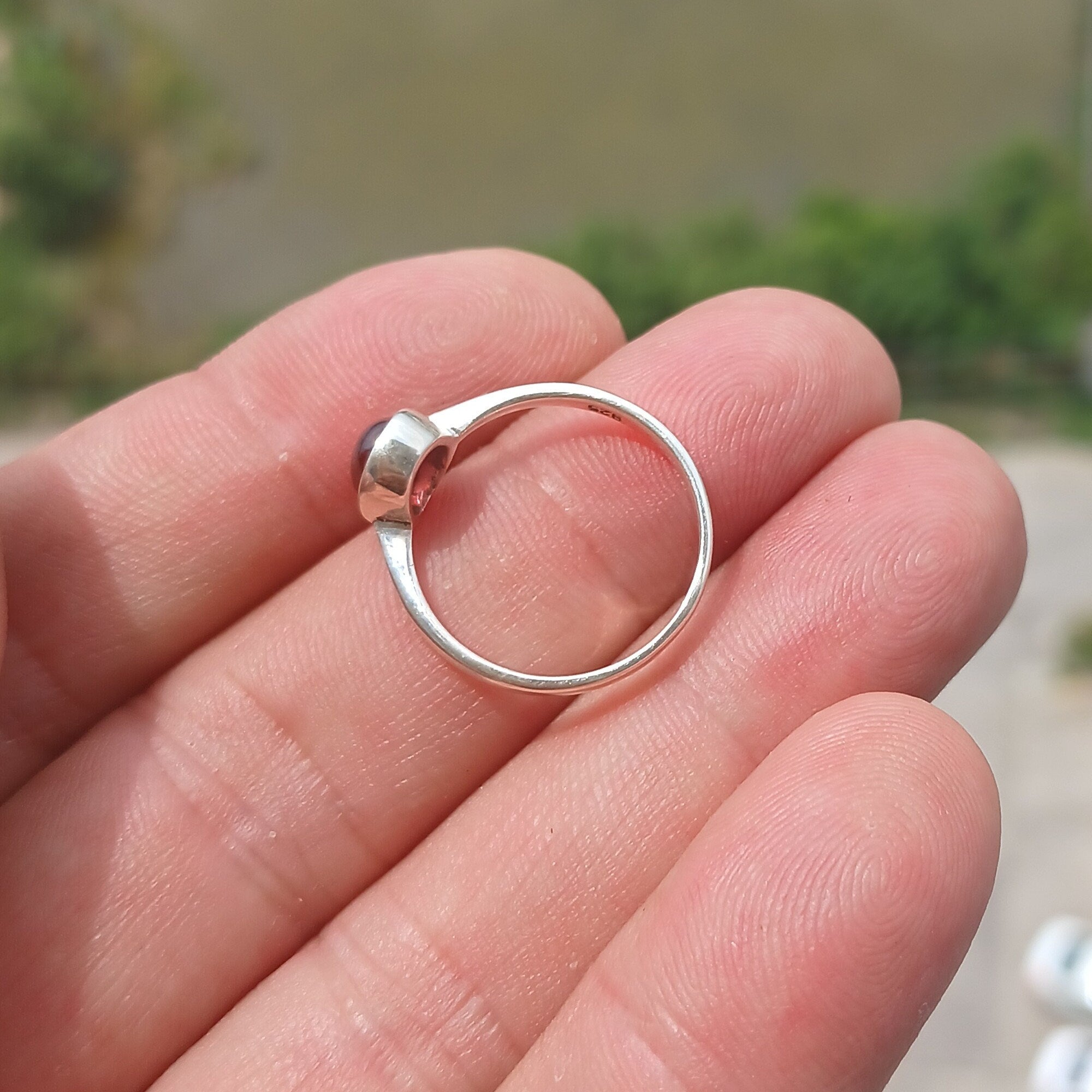 A stunning red Garnet ring set in polished sterling silver, featuring an oval-shaped Garnet cabochon and a sleek band design.