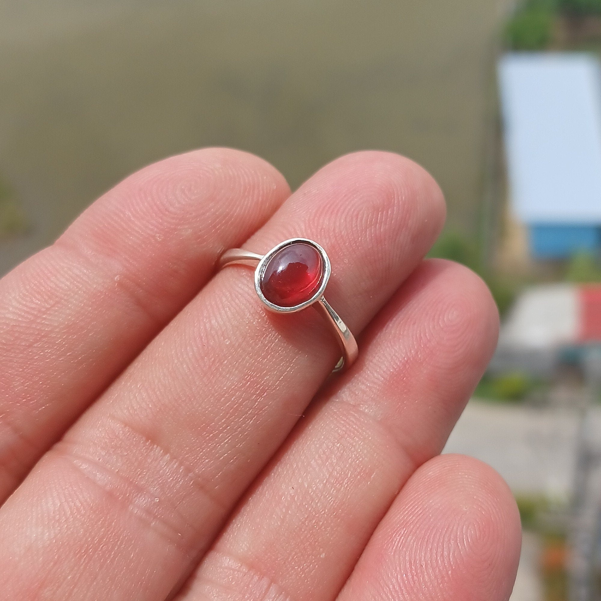 A stunning red Garnet ring set in polished sterling silver, featuring an oval-shaped Garnet cabochon and a sleek band design.