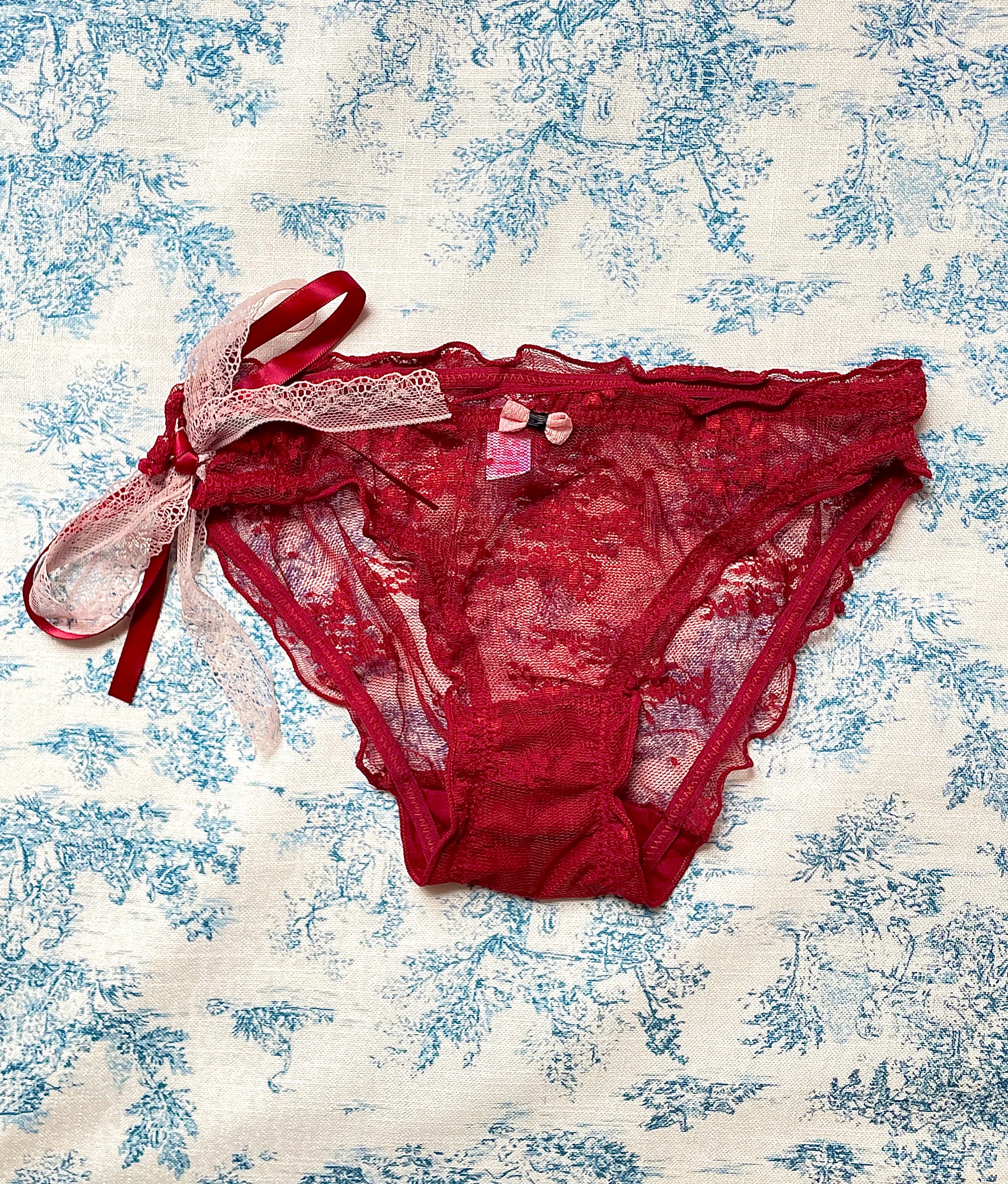 Red Lace Tie Panty featuring a delicate lace design and pink bow detail, showcasing luxurious satin and comfortable cotton lining.