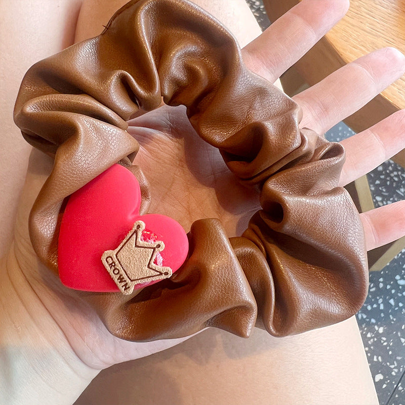 A woman's hand holding a red and white plaid hair tie shaped like a five-pointed star, showcasing its stylish design.