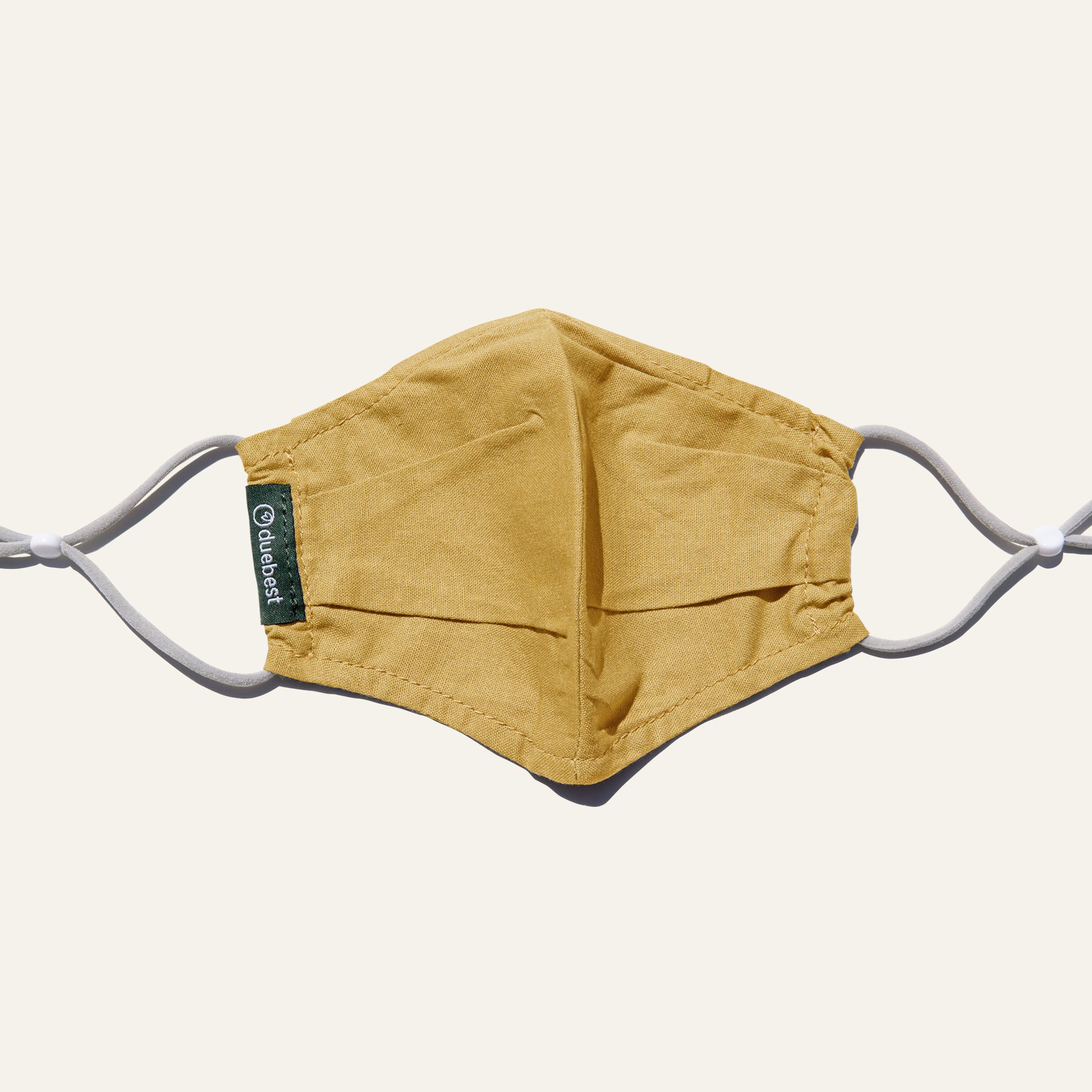 Mustard yellow reusable fabric mask made from cotton and linen blend, featuring adjustable earloops and pleated design for comfort and coverage.