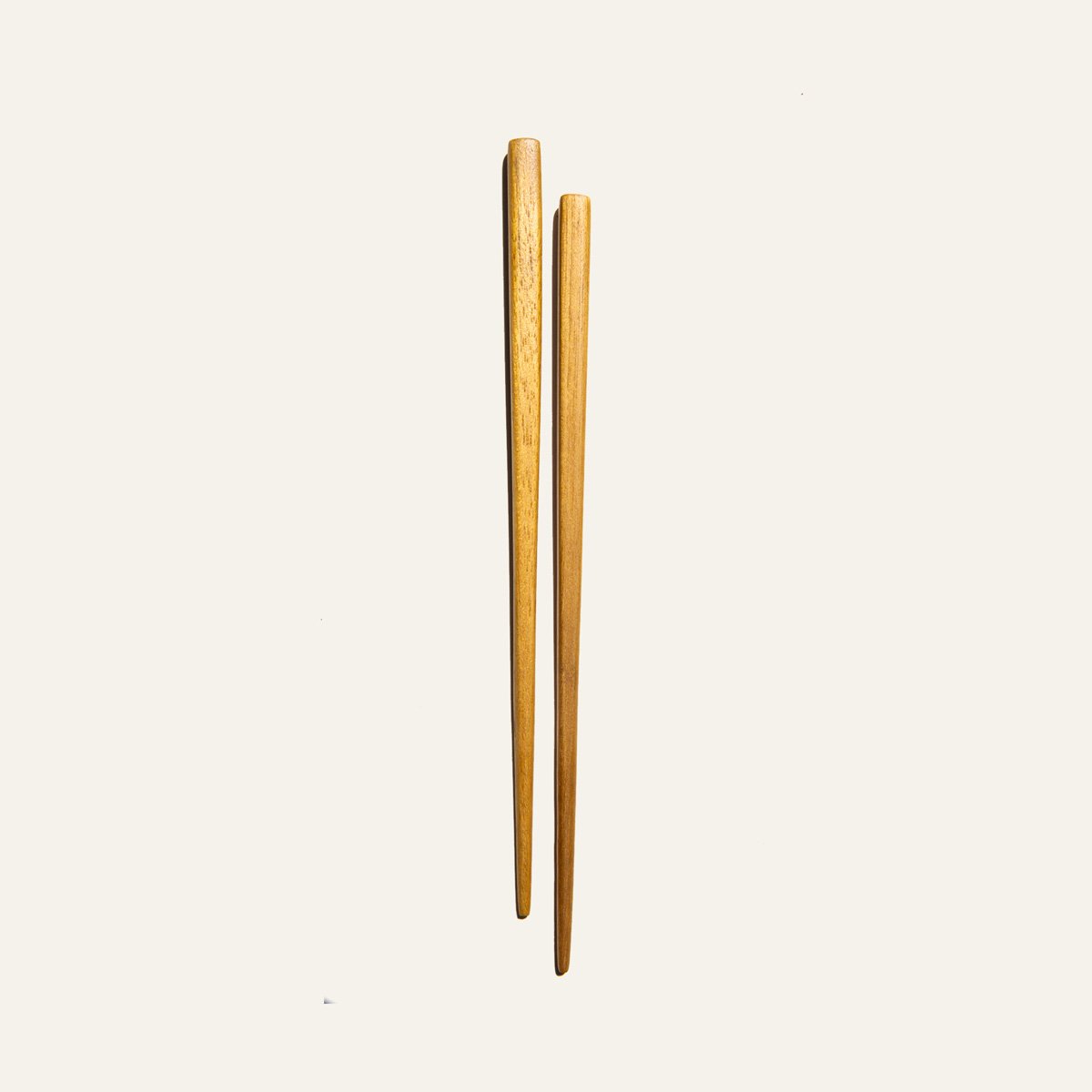 A pair of handcrafted reusable teak wood chopsticks showcasing unique grain patterns, perfect for sustainable dining.