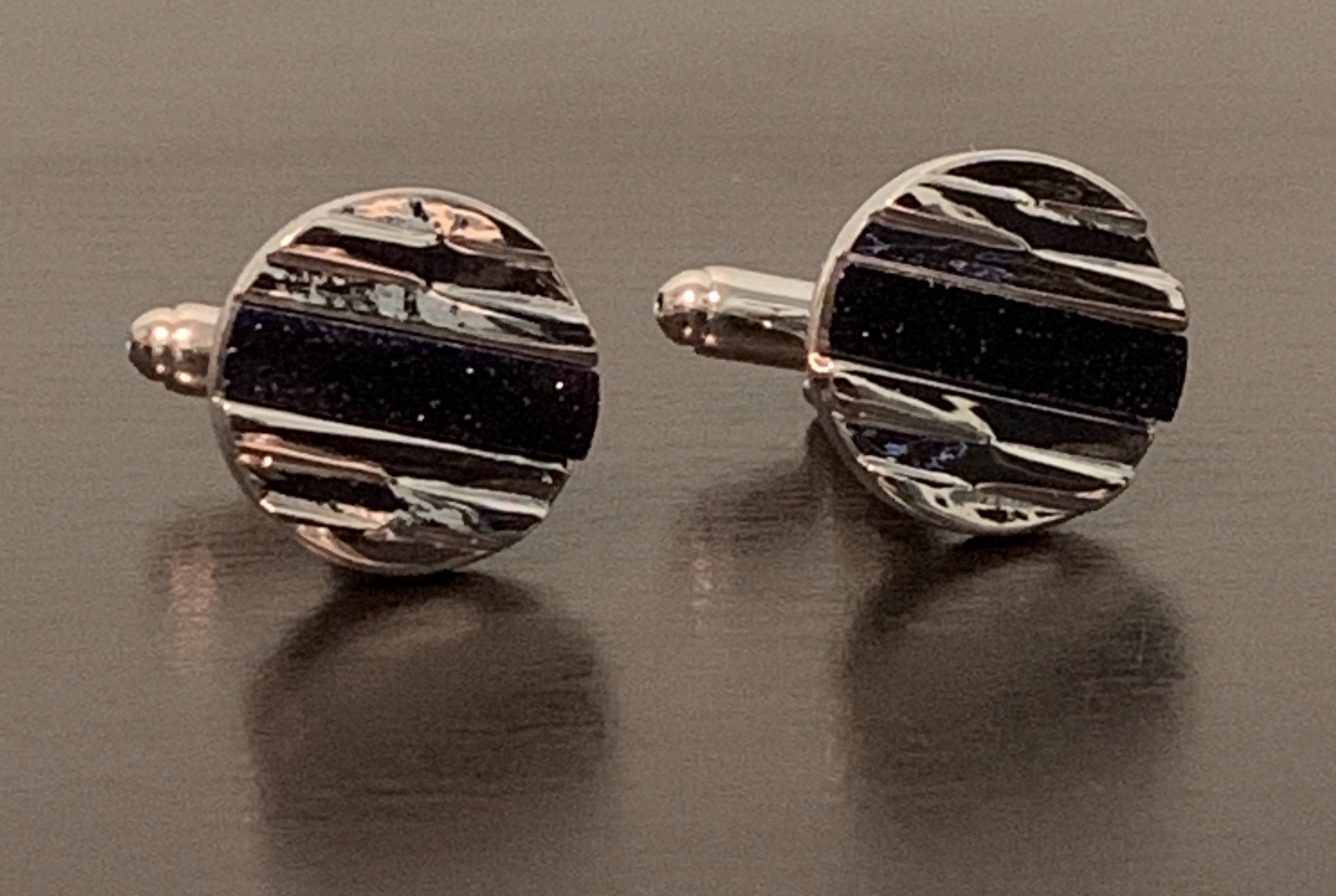 Rock Star Cufflinks featuring hewn silver design and sparkling blue center, symbolizing elegance and individuality.