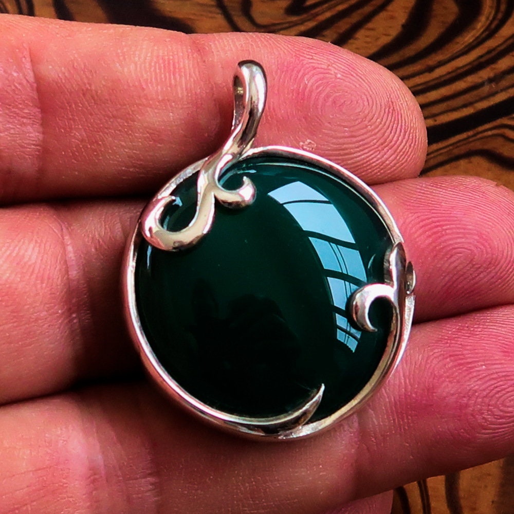 Round Agate Pendant in sterling silver featuring a green Agate cabochon, showcasing intricate design and elegant bail.