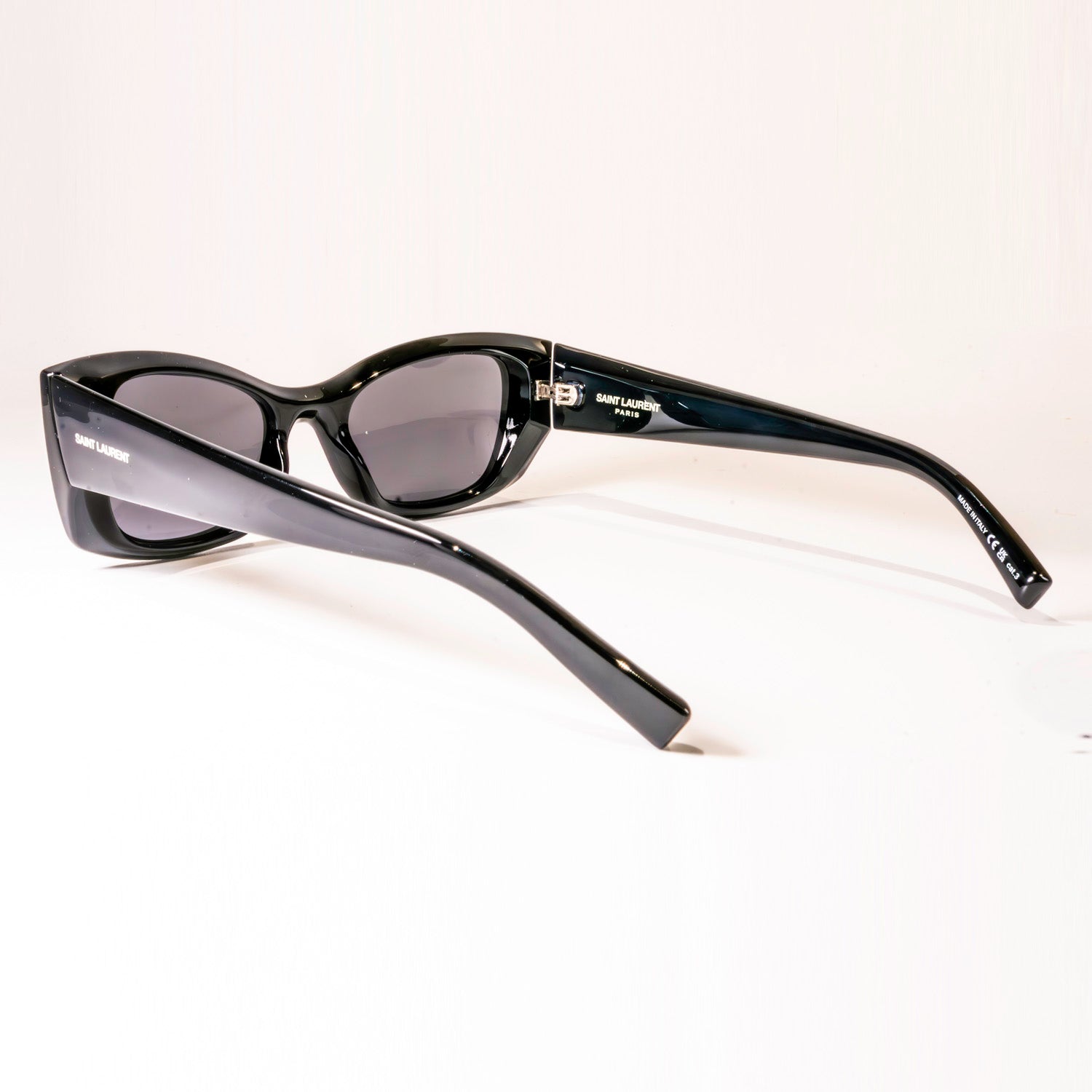 Saint Laurent SL 593 001 sunglasses featuring a black cat-eye frame and black lenses, elegantly displayed in a protective case.