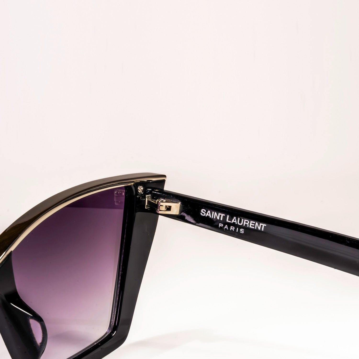 Saint Laurent SL-570 sunglasses featuring a shiny black cat-eye frame with silver accents and grey lenses with a silver mirror finish.