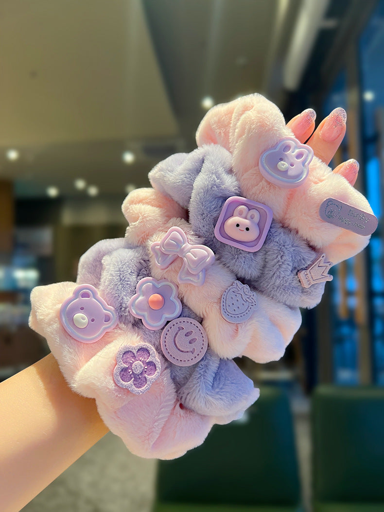 A person holding a set of five vibrant pink and purple scrunchies, showcasing their stylish design and quality material.