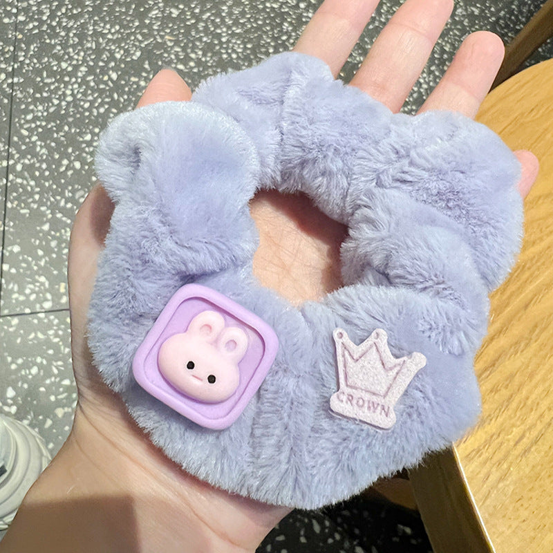 A person holding a set of five vibrant pink and purple scrunchies, showcasing their stylish design and quality material.