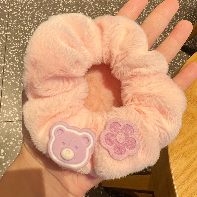 A person holding a set of five vibrant pink and purple scrunchies, showcasing their stylish design and quality material.