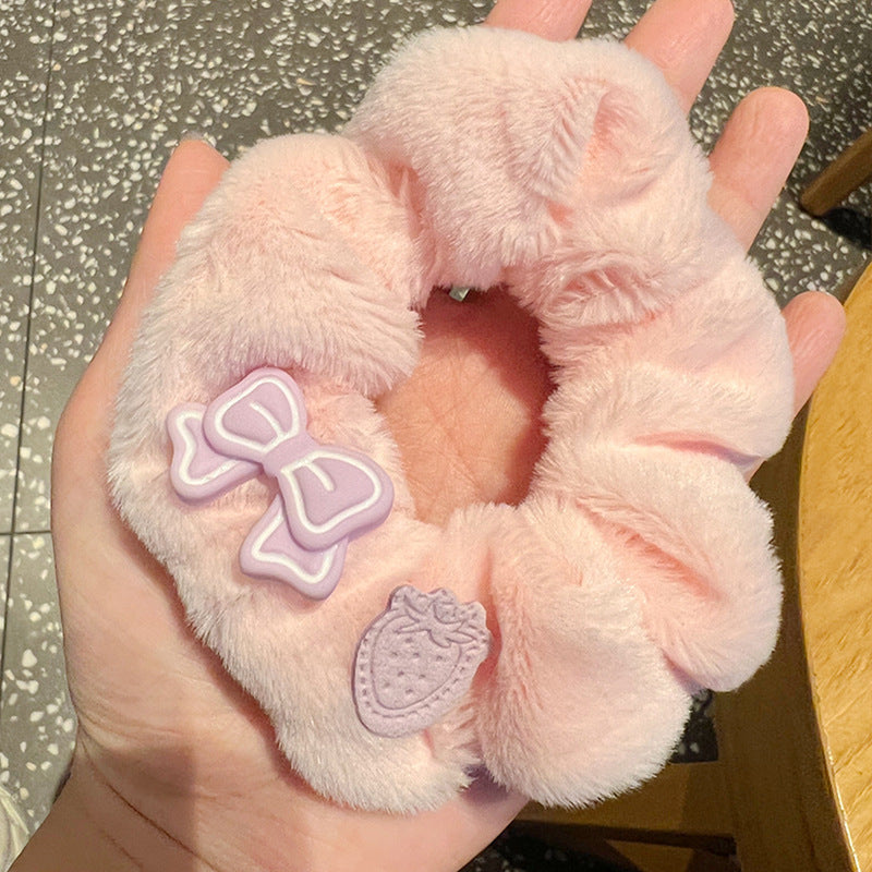 A person holding a set of five vibrant pink and purple scrunchies, showcasing their stylish design and quality material.