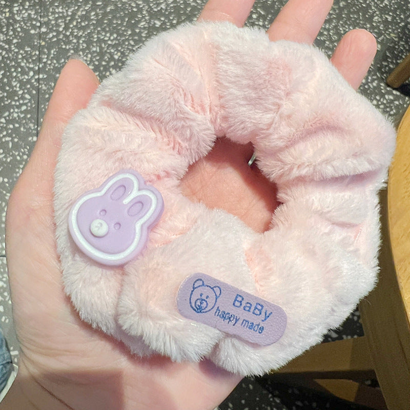 A person holding a set of five vibrant pink and purple scrunchies, showcasing their stylish design and quality material.