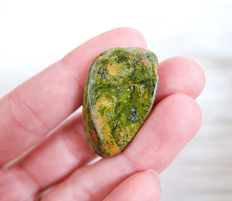 A set of 10 tumbled green unakite crystals, showcasing their unique colors and textures, ideal for spiritual practices and crystal grids.