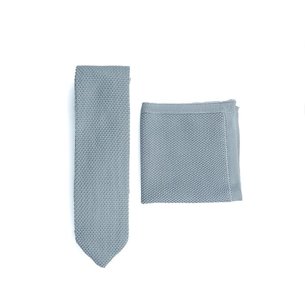 A stylish silver knitted tie and matching pocket square set displayed elegantly, showcasing their texture and design.