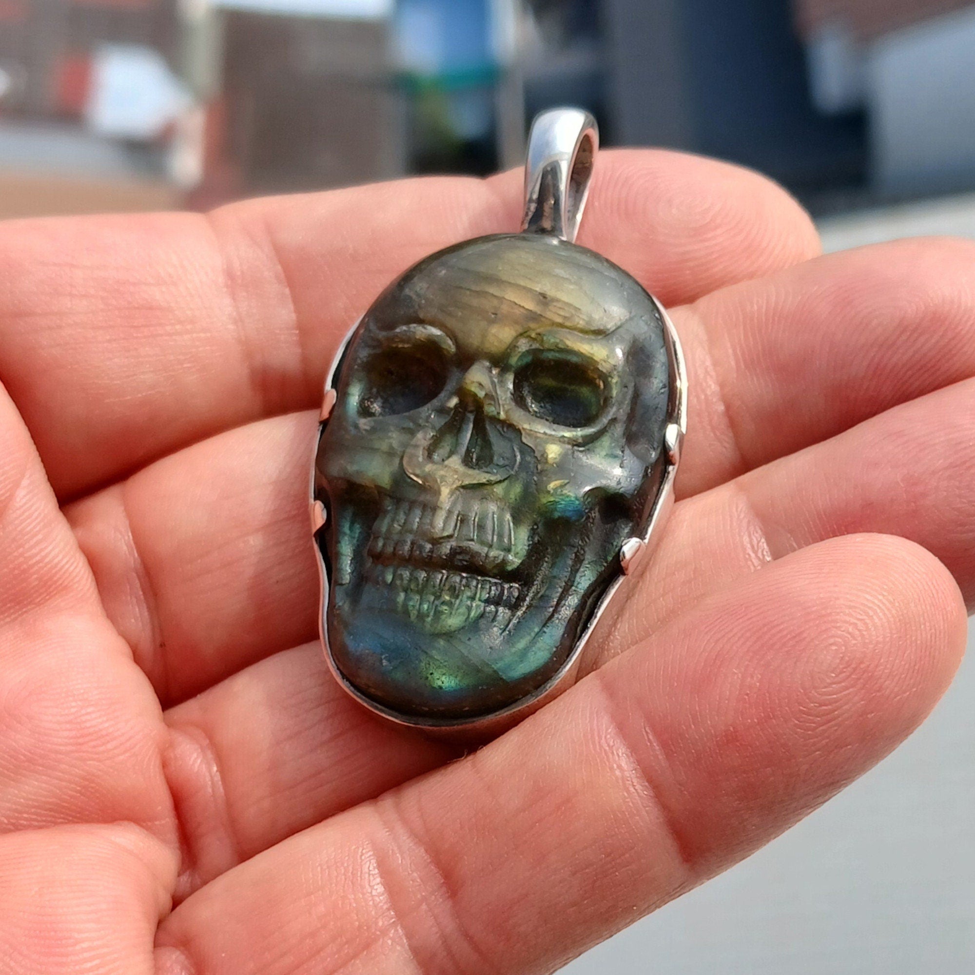 Handcrafted sterling silver skull pendant featuring a Labradorite carving, polished to a mirror finish, showcasing intricate details.