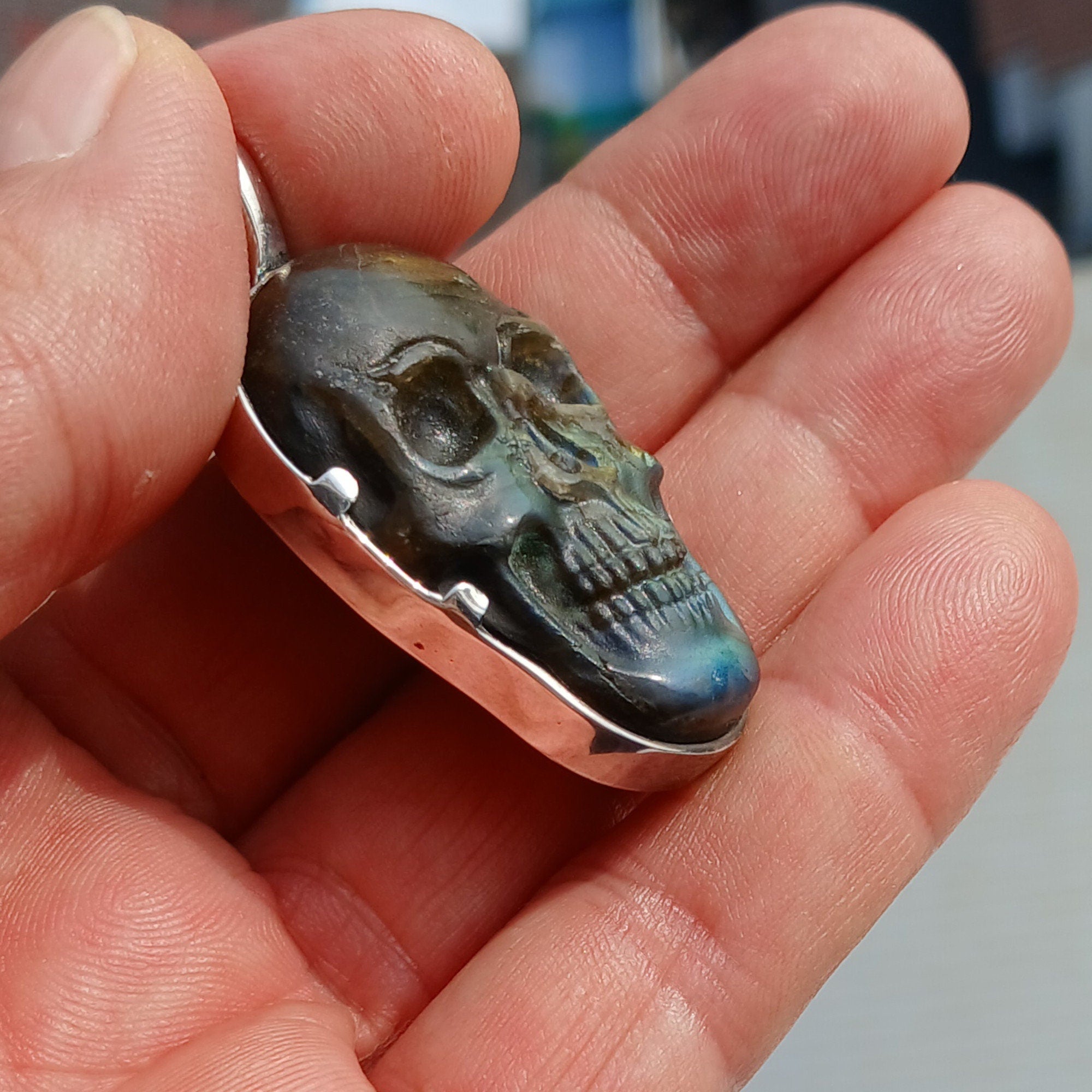 Handcrafted sterling silver skull pendant featuring a Labradorite carving, polished to a mirror finish, showcasing intricate details.