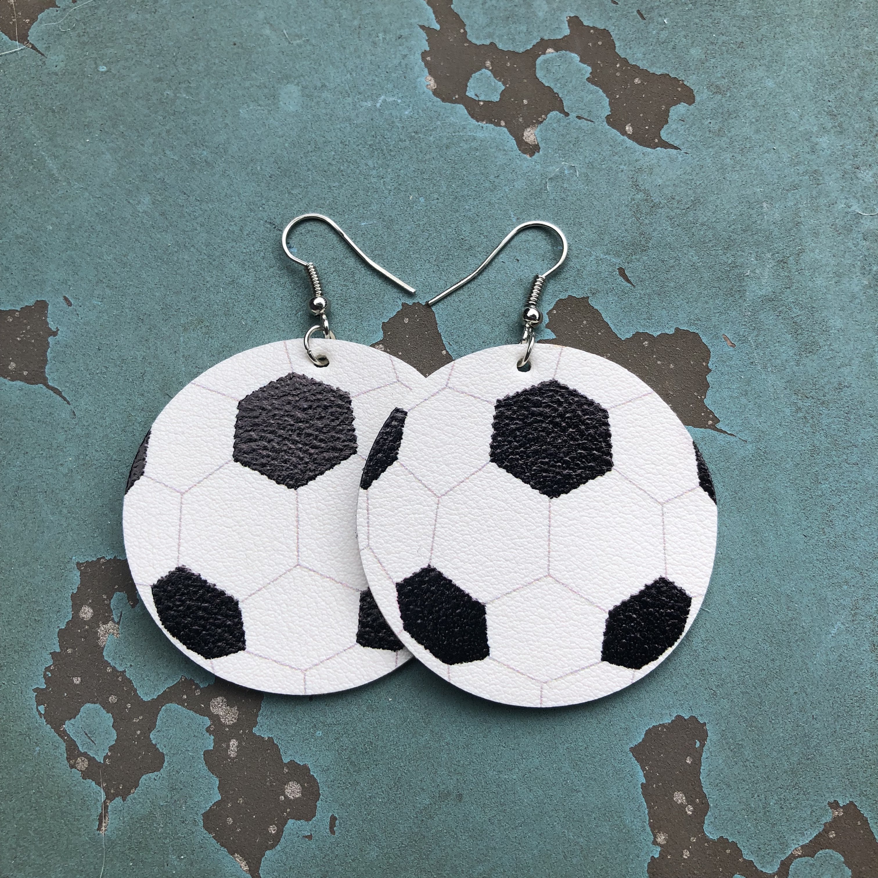 Soccer-themed faux leather hang earrings with a 2-inch design, featuring nickel and lead-free hooks.