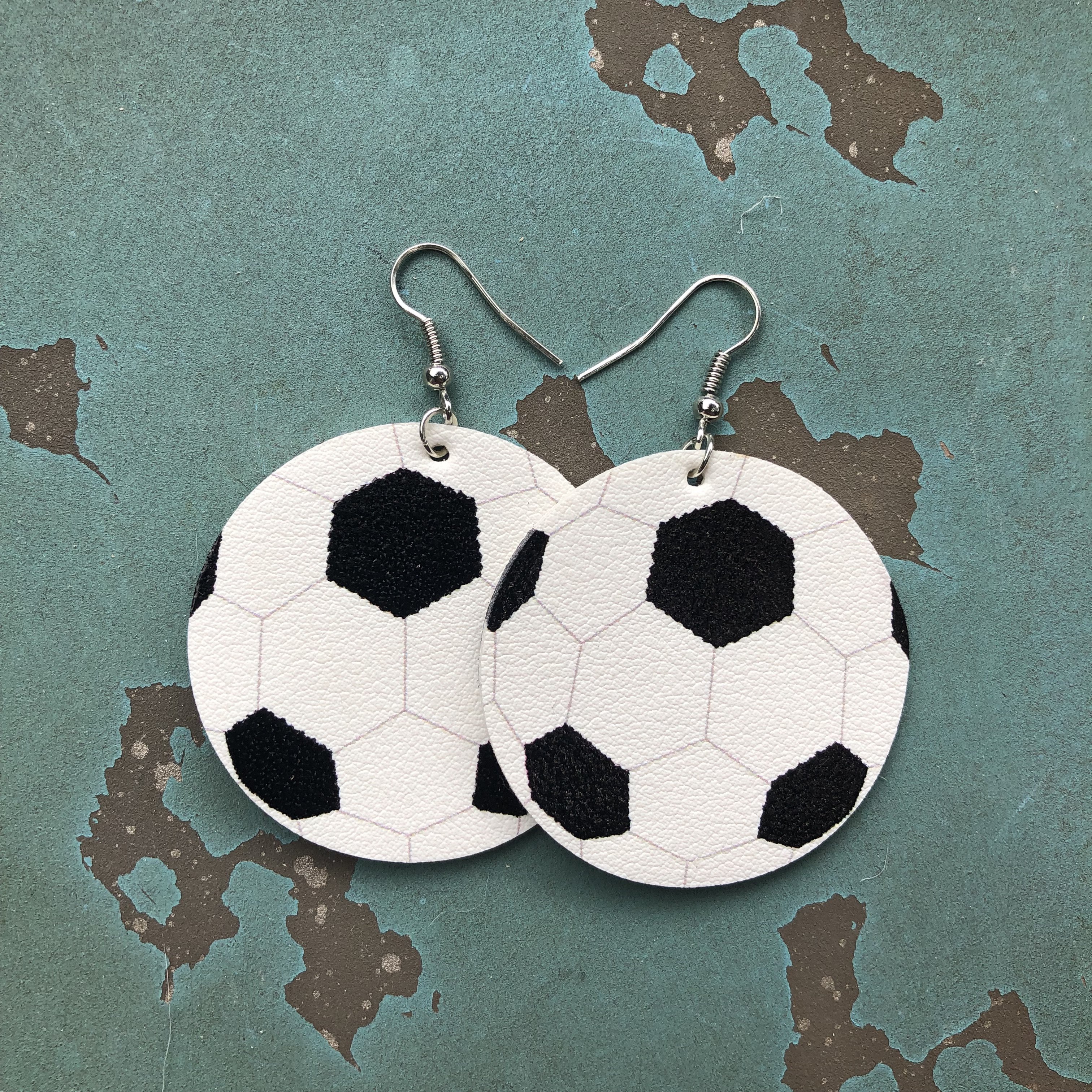 Soccer-themed faux leather hang earrings with a 2-inch design, featuring nickel and lead-free hooks.