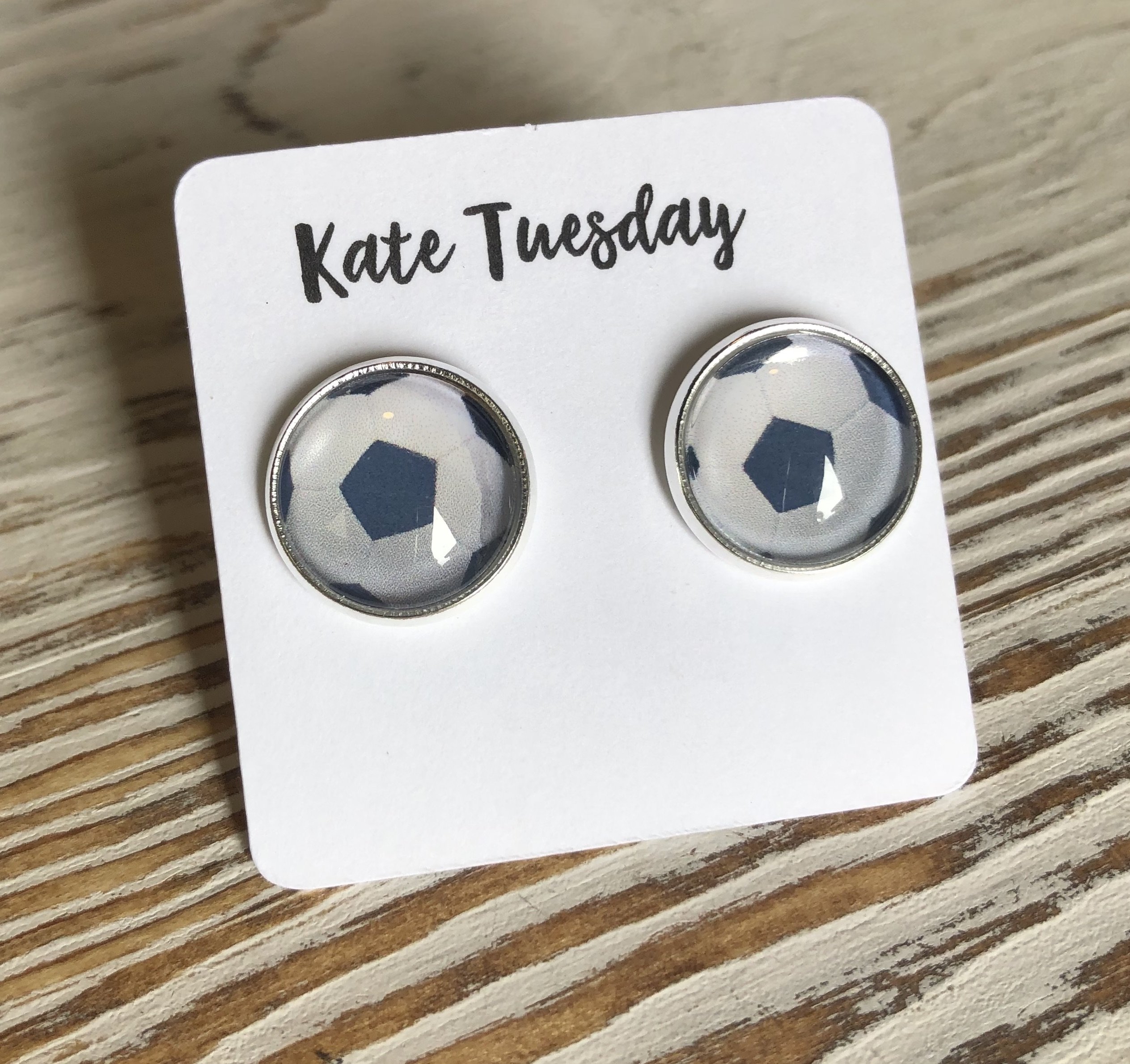 A pair of 12mm soccer ball stud earrings, lead and nickel free, showcasing a sporty design.