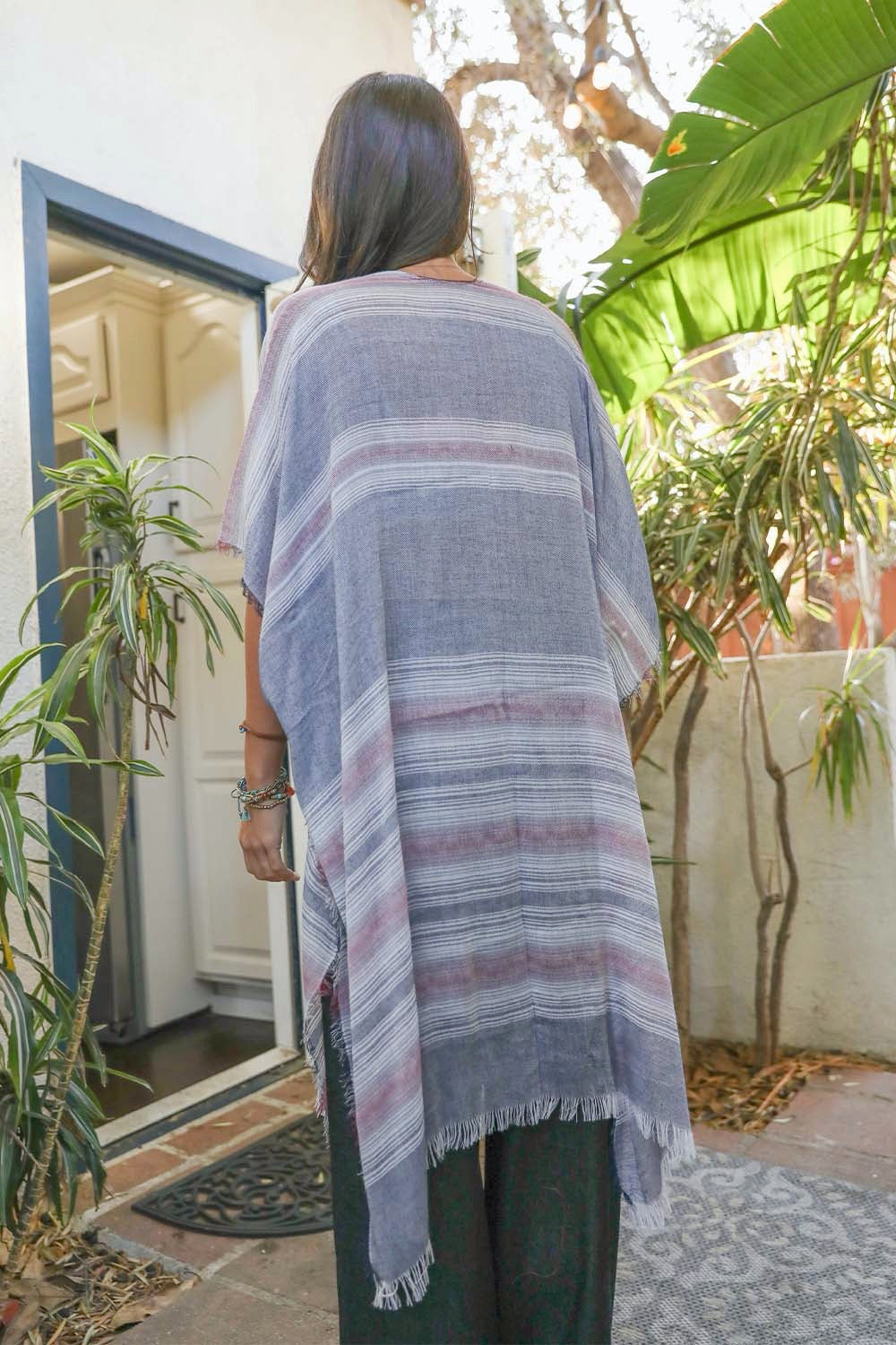 A vibrant striped frayed kimono featuring colorful patterns, perfect for layering and keeping warm on cool nights.