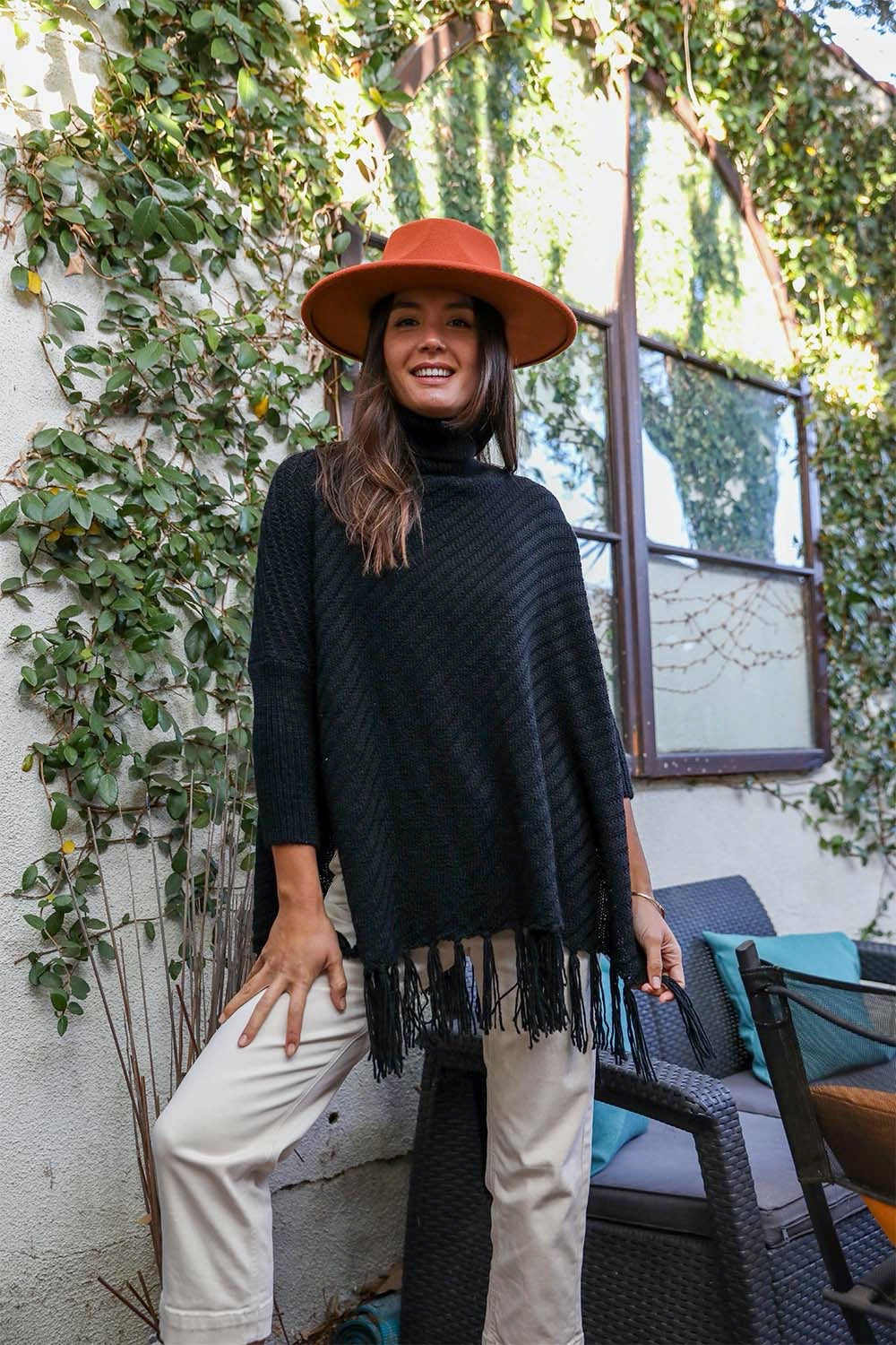 A cozy roll-neck poncho in a stylish knit fabric with a frayed hem, perfect for winter layering.