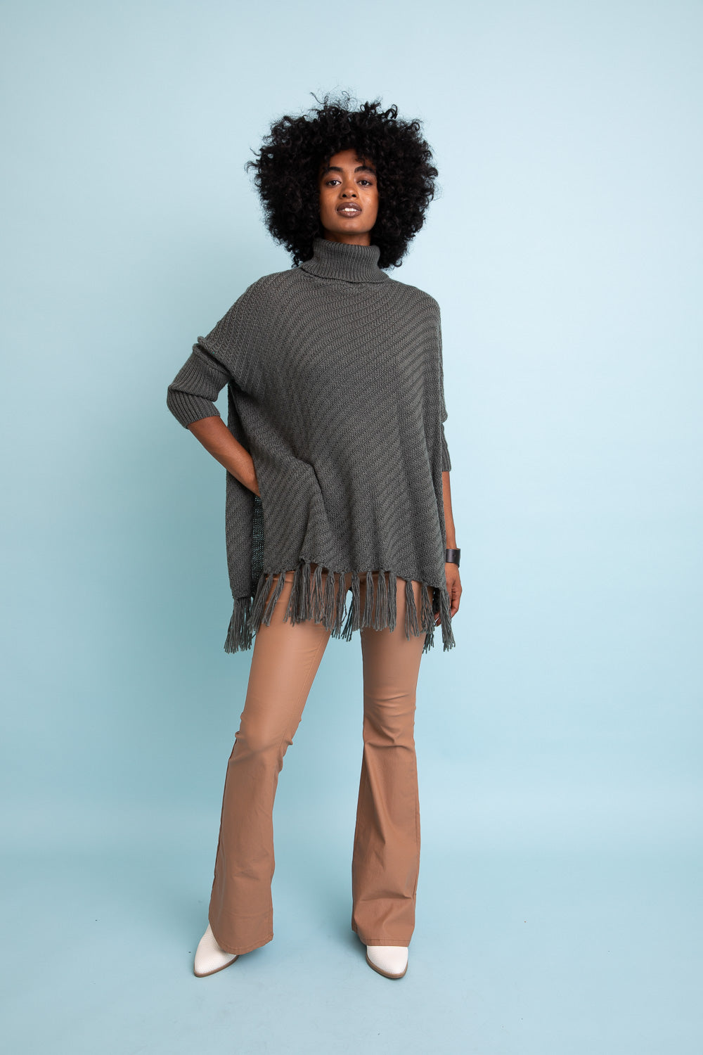 A cozy roll-neck poncho in a stylish knit fabric with a frayed hem, perfect for winter layering.