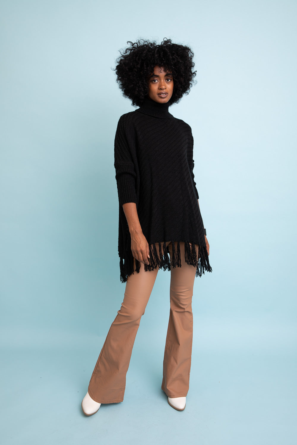 A cozy roll-neck poncho in a stylish knit fabric with a frayed hem, perfect for winter layering.