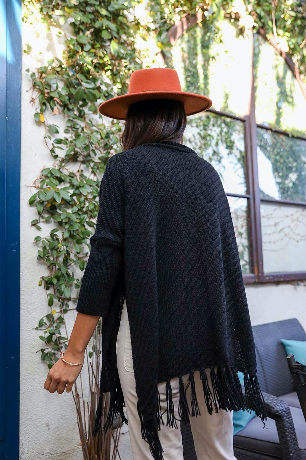 A cozy roll-neck poncho in a stylish knit fabric with a frayed hem, perfect for winter layering.