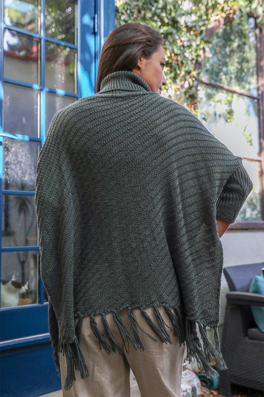 A cozy roll-neck poncho in a stylish knit fabric with a frayed hem, perfect for winter layering.