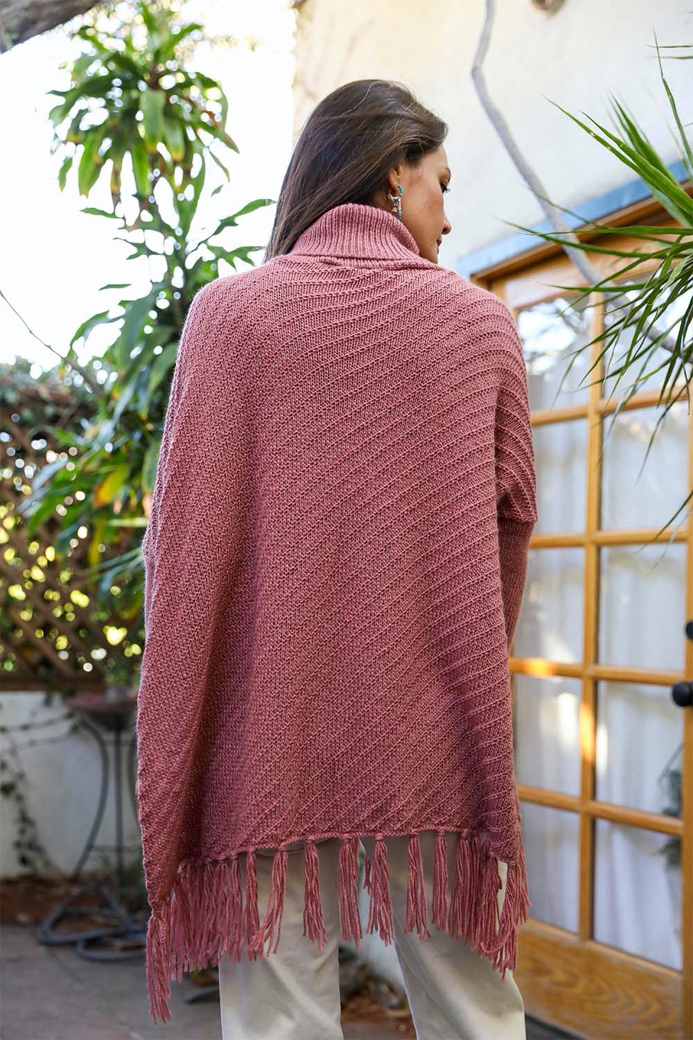 A cozy roll-neck poncho in a stylish knit fabric with a frayed hem, perfect for winter layering.