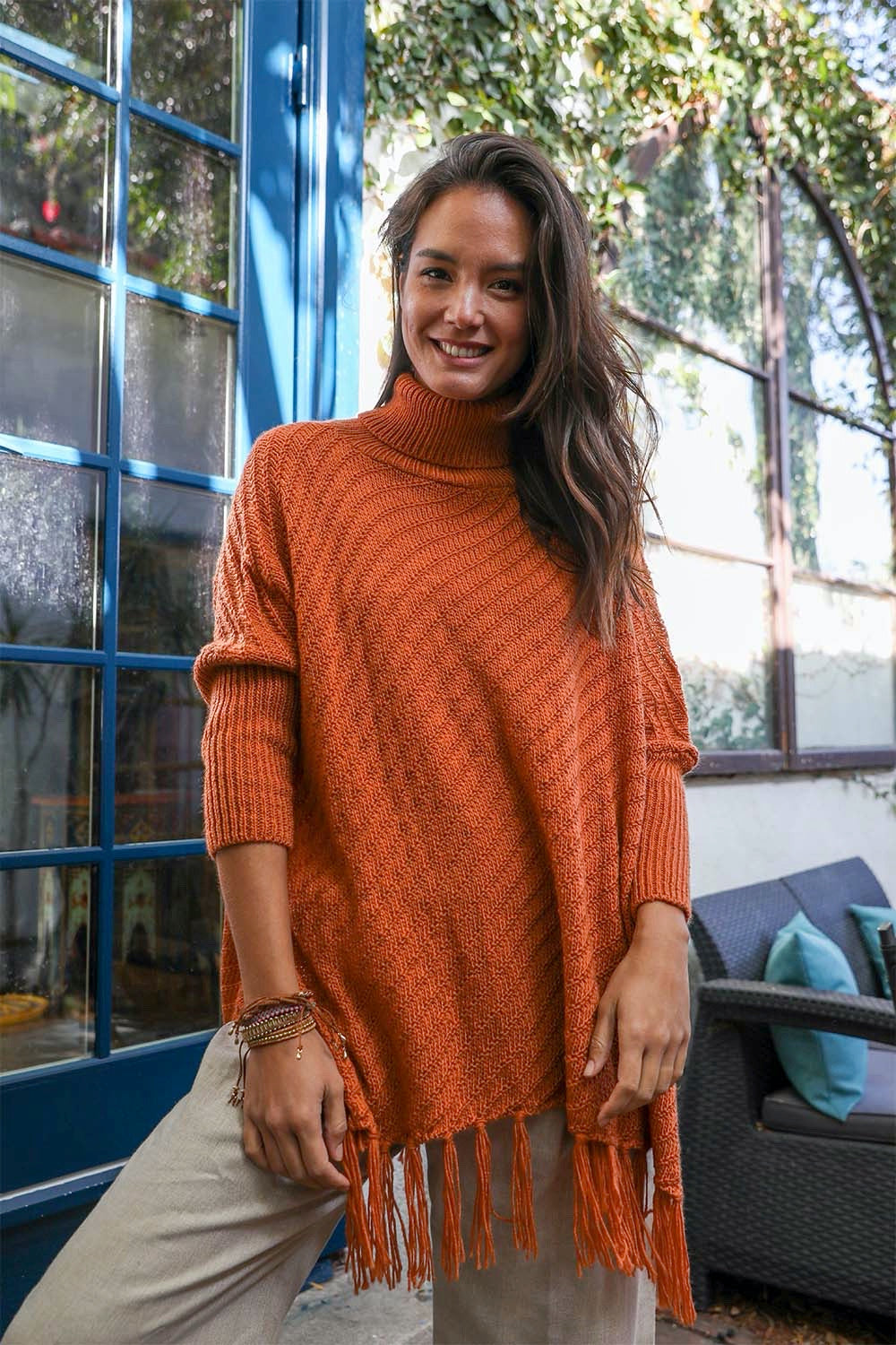 A cozy roll-neck poncho in a stylish knit fabric with a frayed hem, perfect for winter layering.