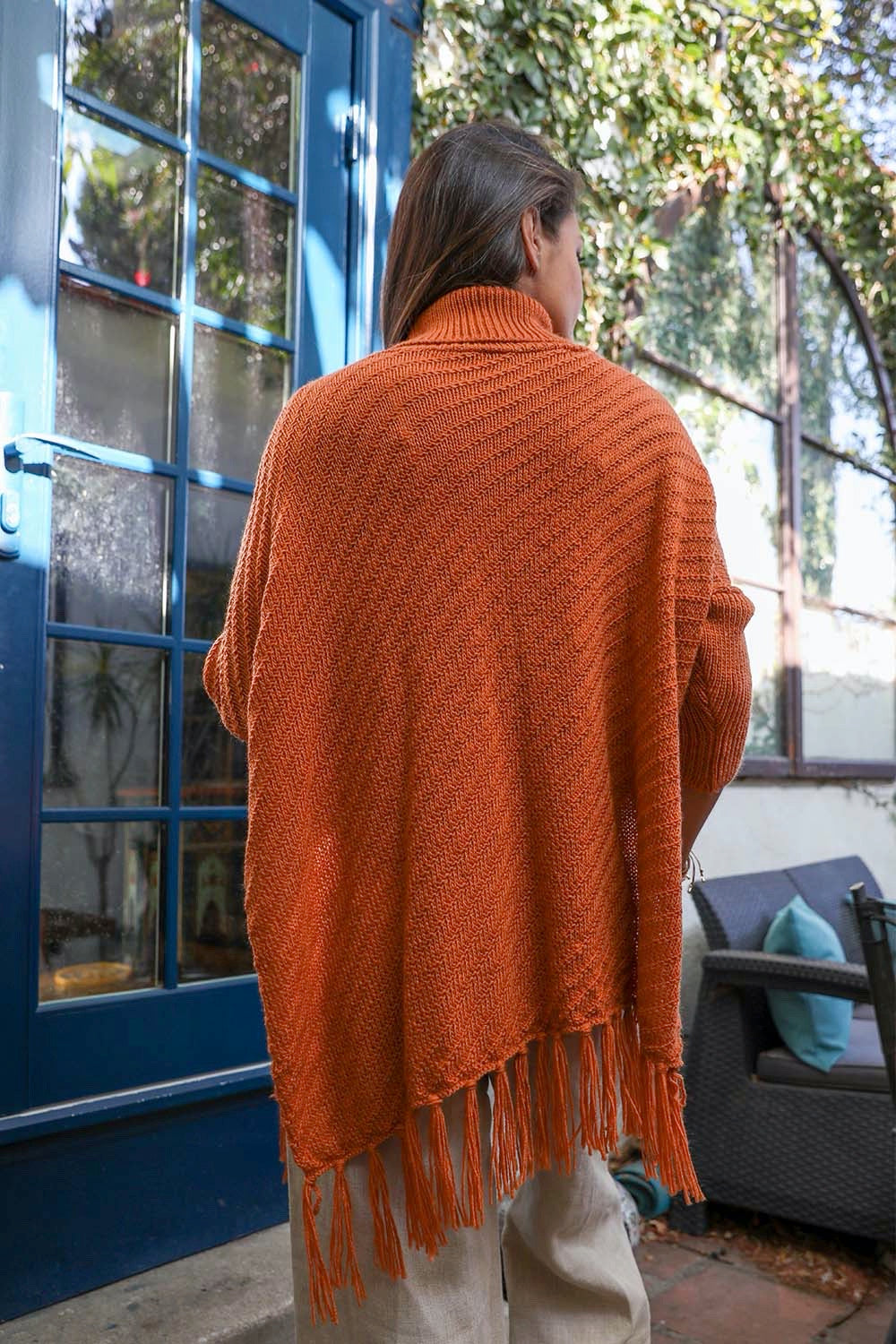 A cozy roll-neck poncho in a stylish knit fabric with a frayed hem, perfect for winter layering.