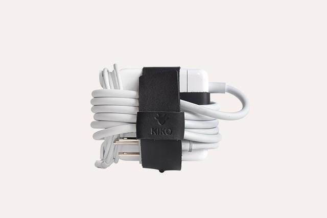 The Mac Cord Lord, a stylish leather cord organizer for MacBook chargers, featuring an adjustable cross-strap design.