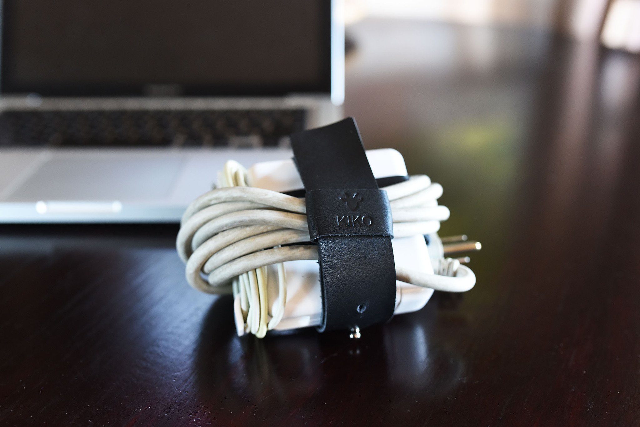 The Mac Cord Lord, a stylish leather cord organizer for MacBook chargers, featuring an adjustable cross-strap design.