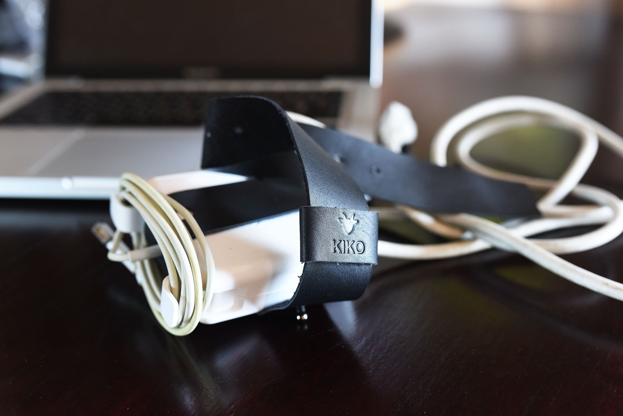 The Mac Cord Lord, a stylish leather cord organizer for MacBook chargers, featuring an adjustable cross-strap design.