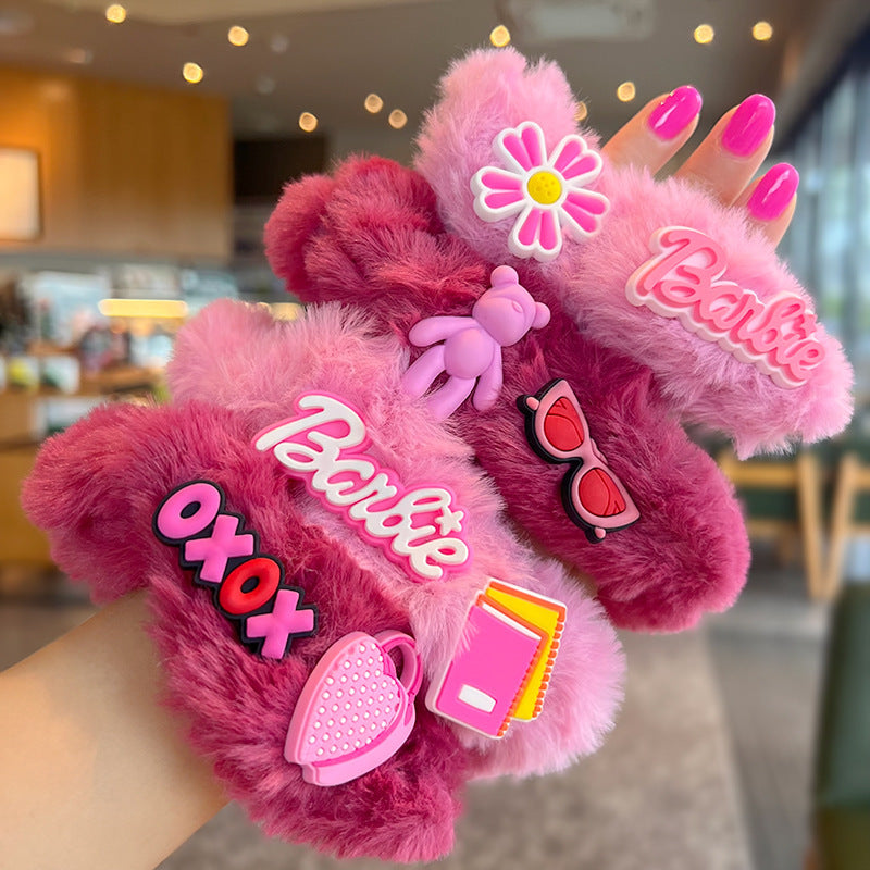 A woman's hand holding four pink fuzzy scrunchies, showcasing their soft texture and stylish design.